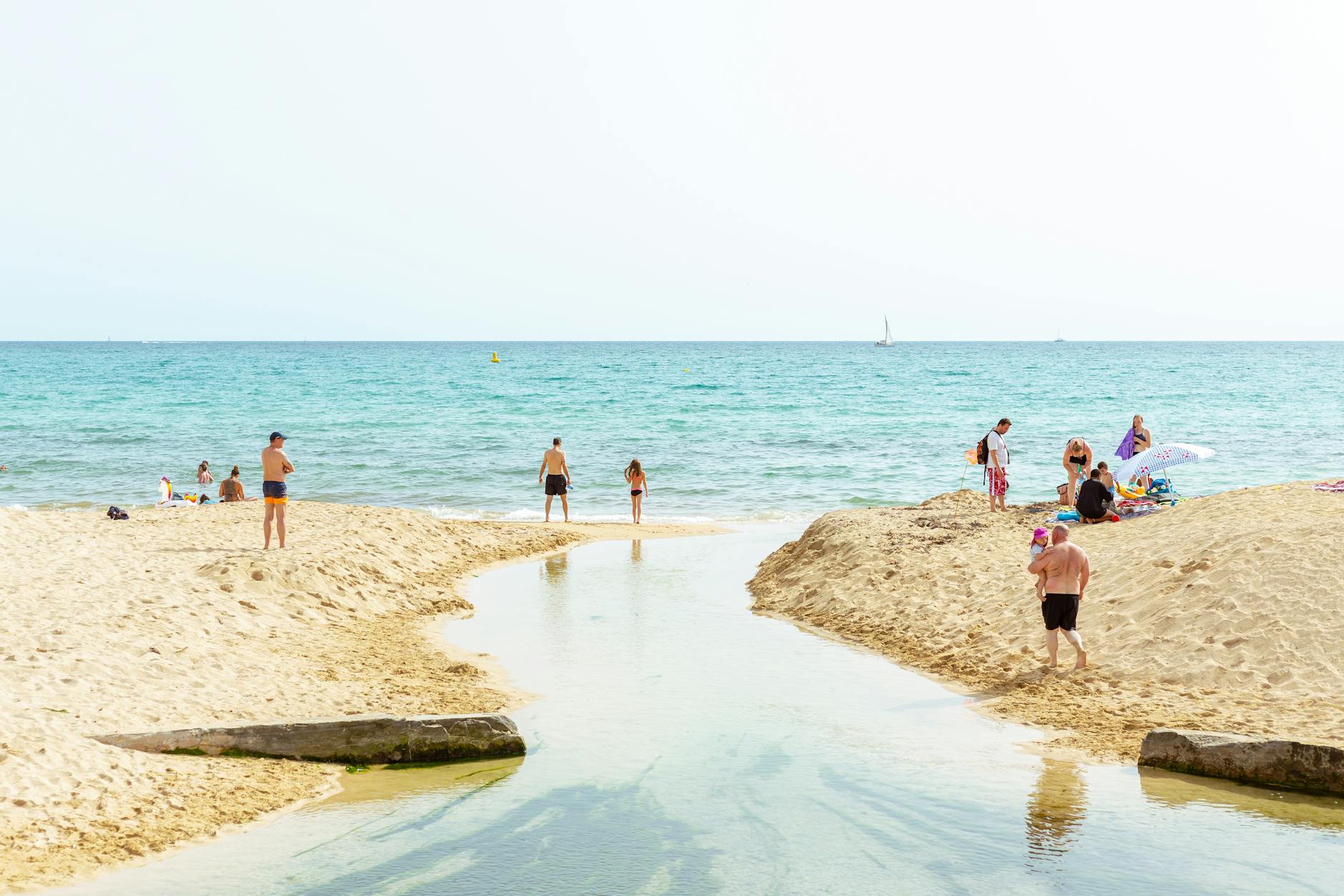 Rodzina z dziećmi na piaszczystej plaży na Majorce z turkusową wodą