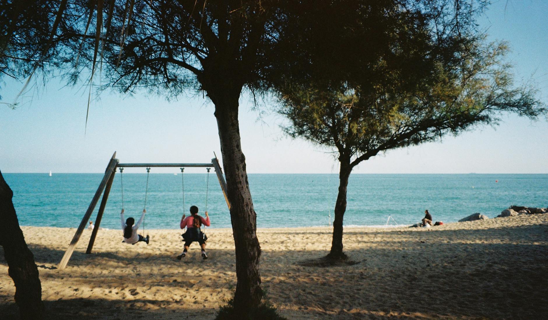 Rodzina z dziećmi na złocistej plaży w Hiszpanii, morze i błękitne niebo w tle