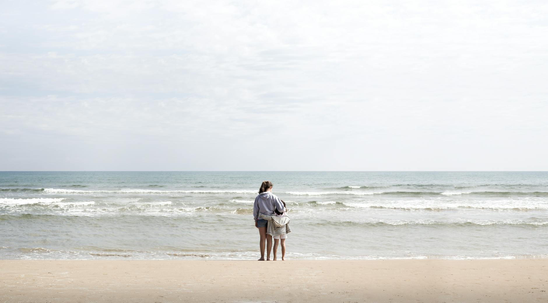 Dzieci bawiące się na piaszczystej plaży w Walencji z turkusowym morzem w tle