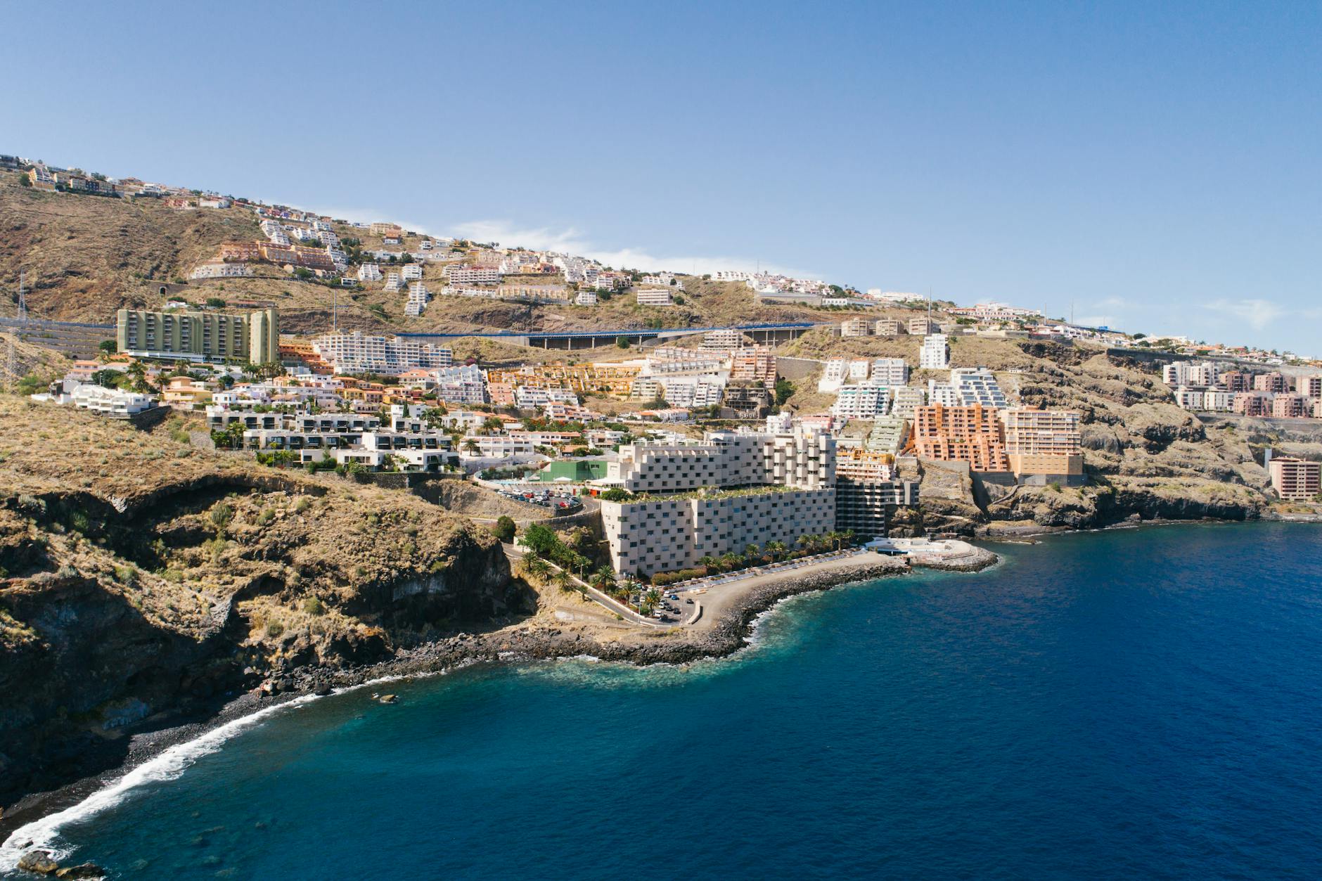 Stunning aerial view of Tenerife coastline with resorts and ocean under clear blue sky.