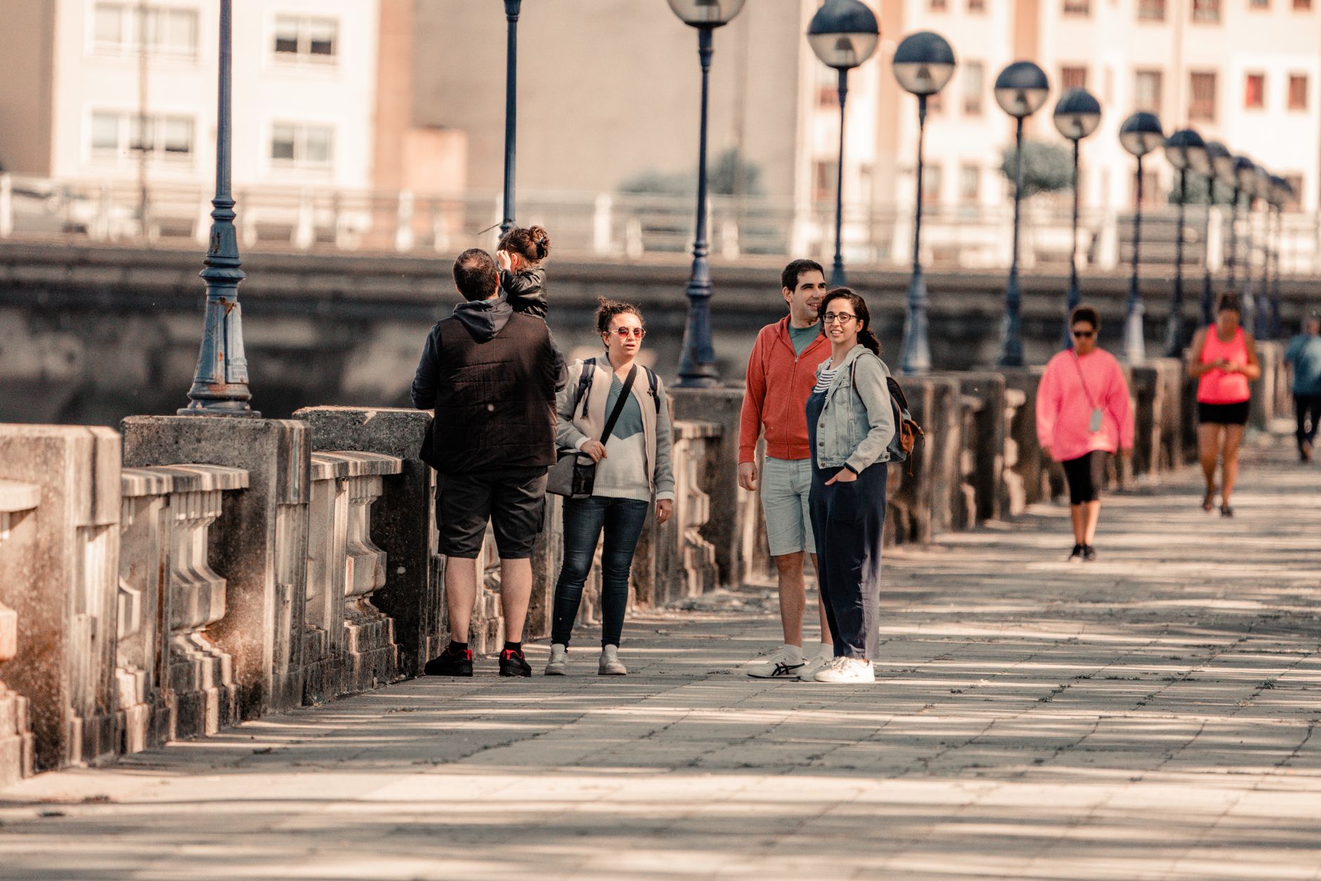 Group of people enjoying a sunny walk on a promenade in Burgo, Spain.