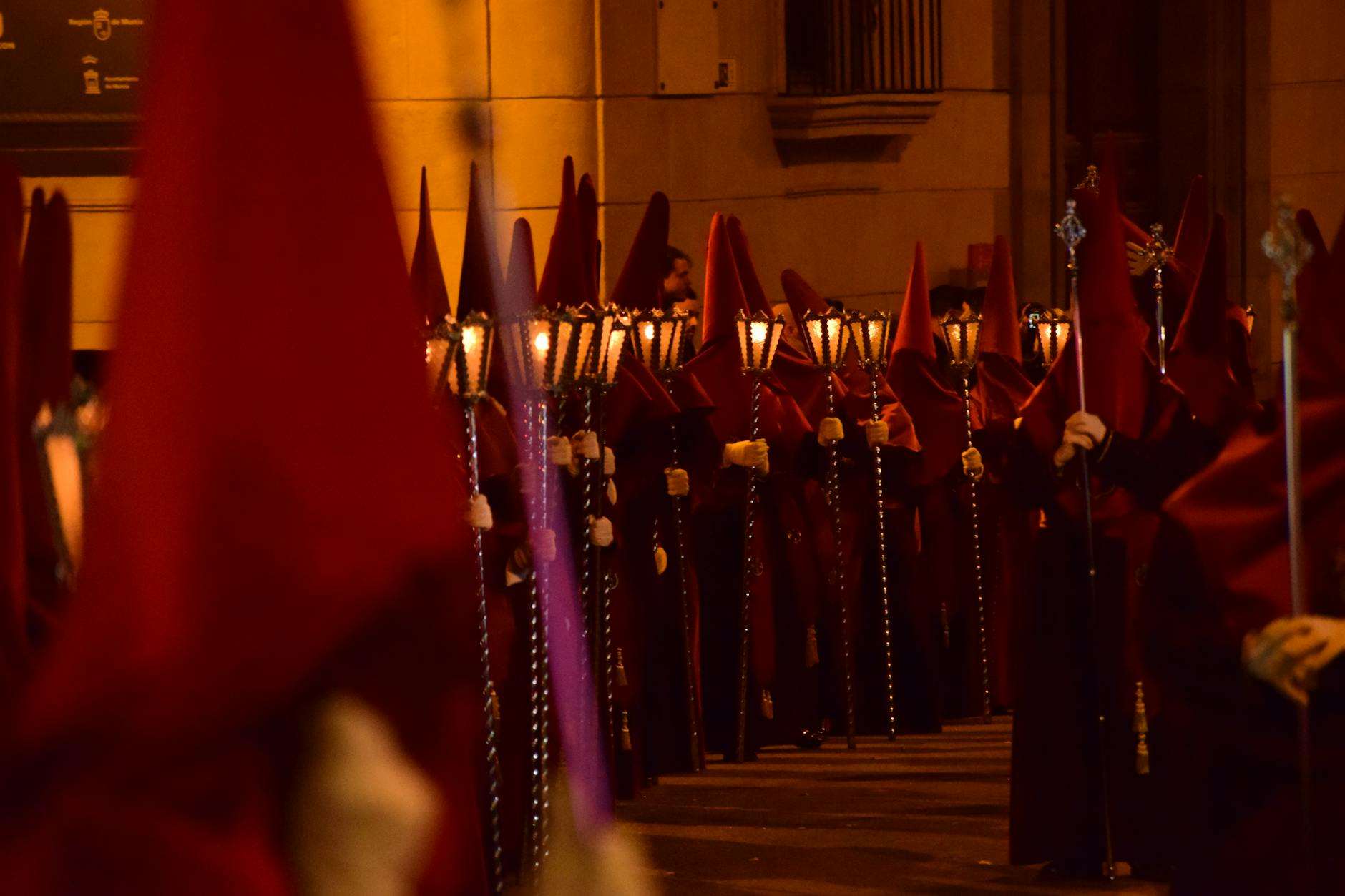Traditional Easter procession in Murcia with hooded figures carrying lanterns at night.