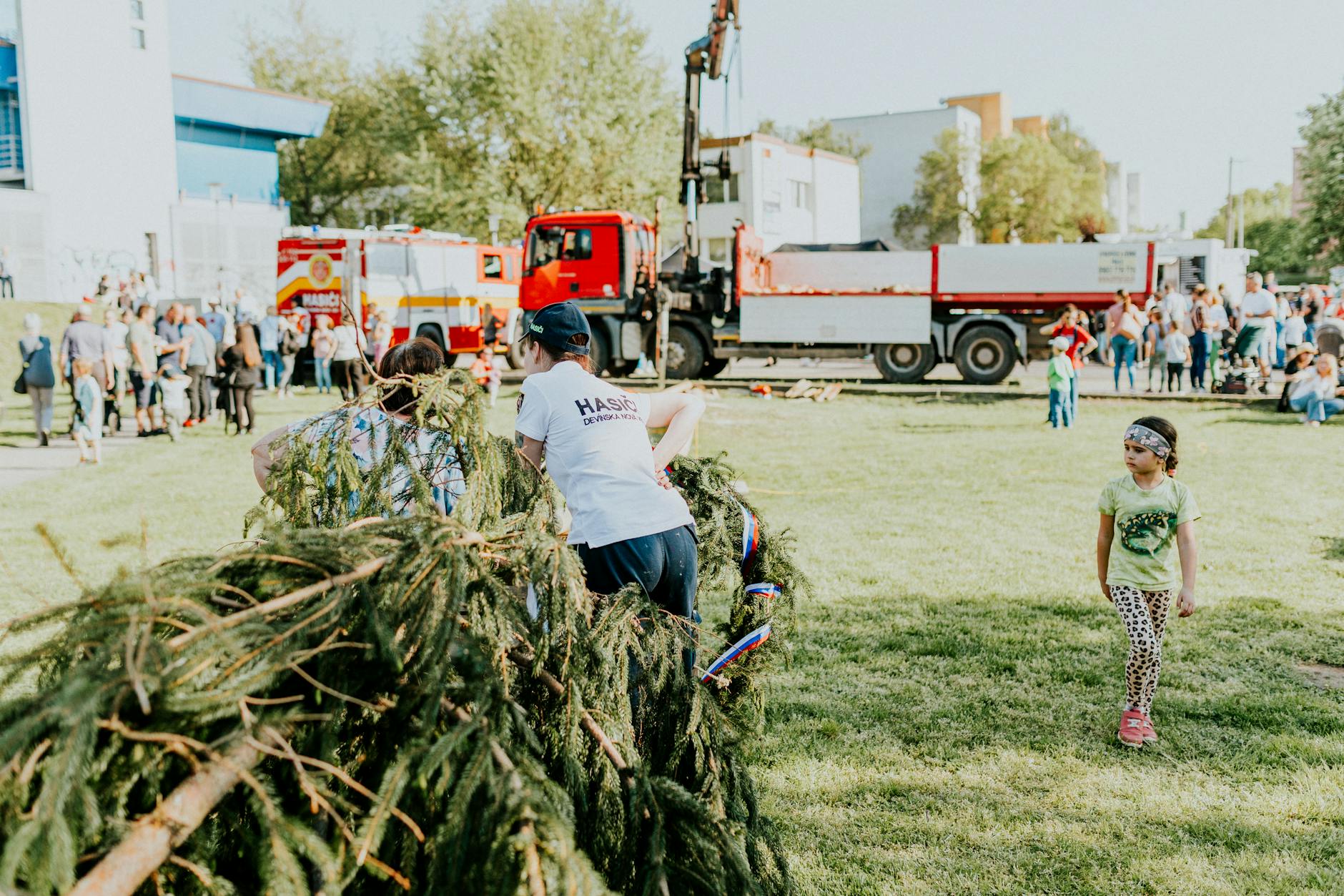 A lively outdoor community event featuring fire trucks, families, and a festive atmosphere.