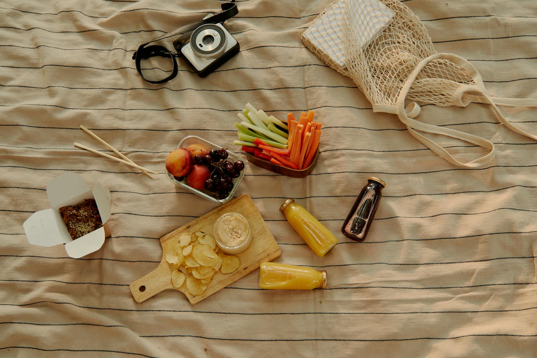 An inviting outdoor picnic featuring fruits, juices, and snacks on a blanket.