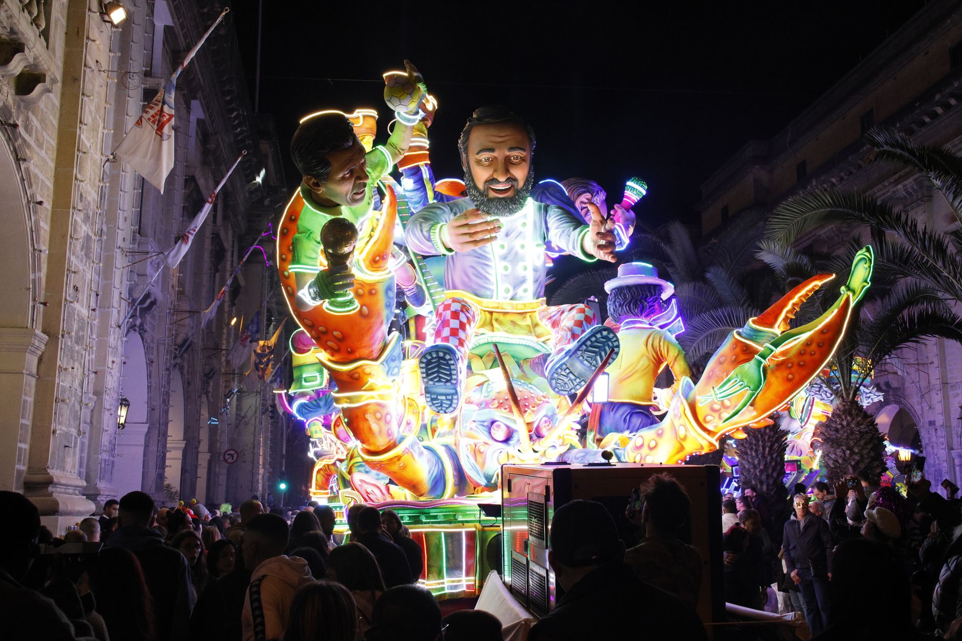 Colorful illuminated float attracts crowd at night parade.