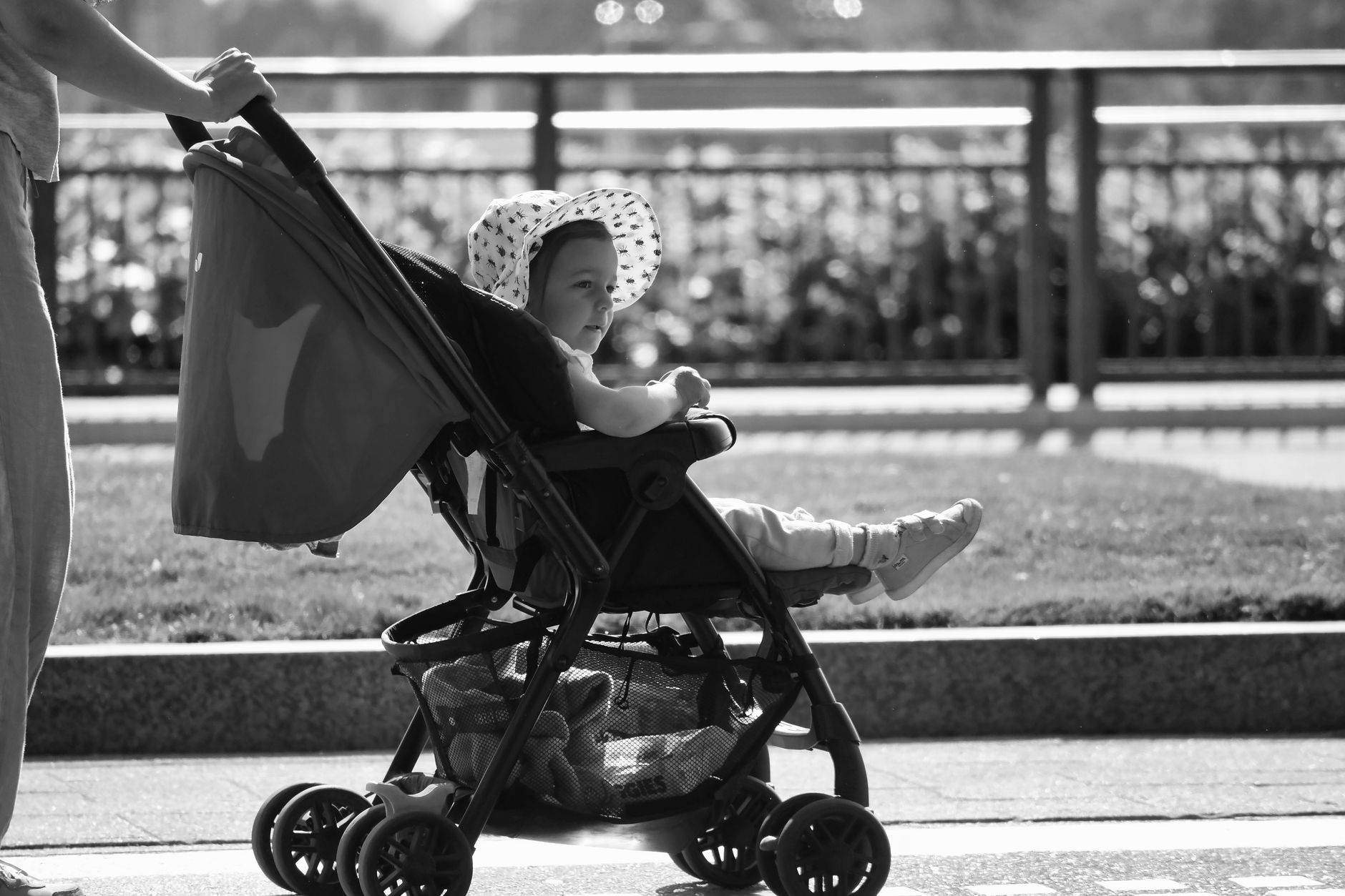 Adorable baby in a sun hat enjoys a stroll in a stroller, black and white urban setting.