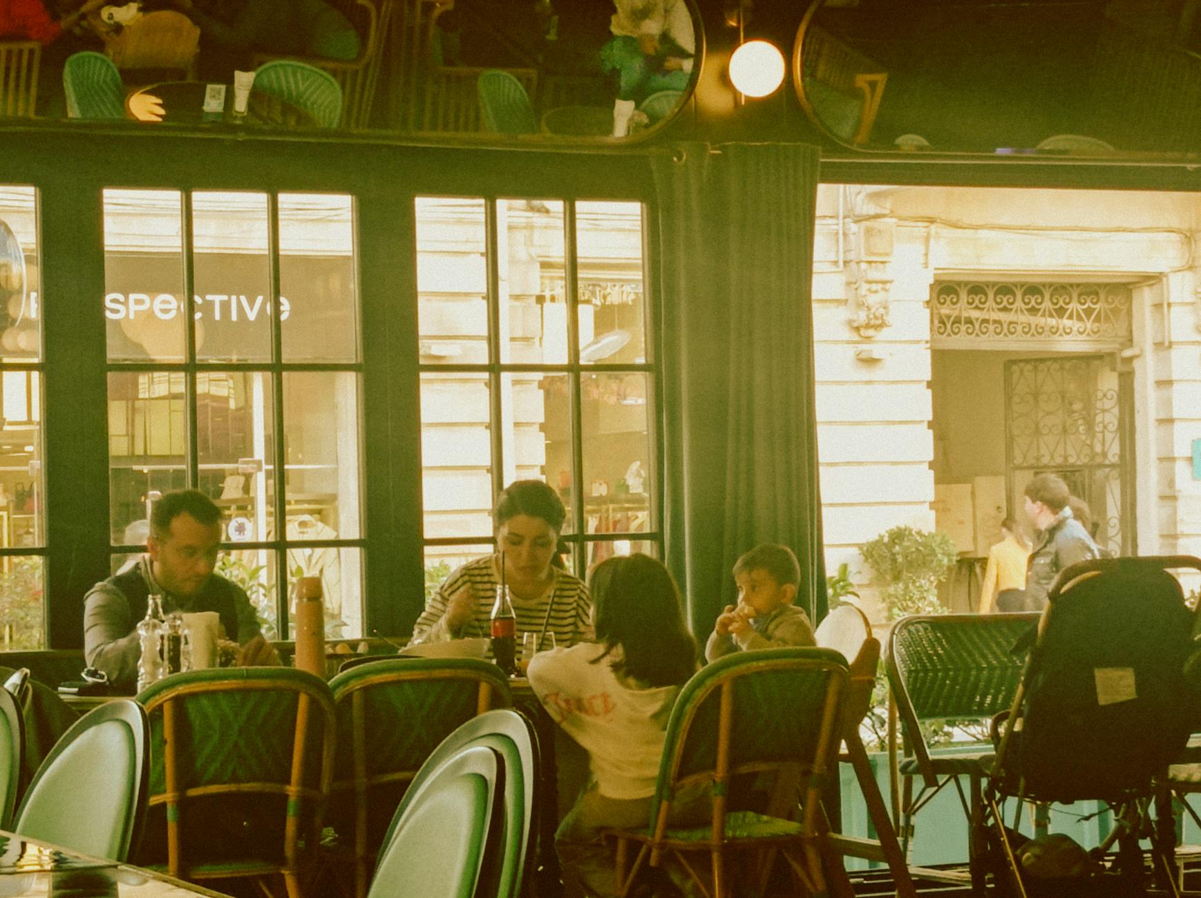 A family shares a meal in a charming cafe, enjoying quality time together.