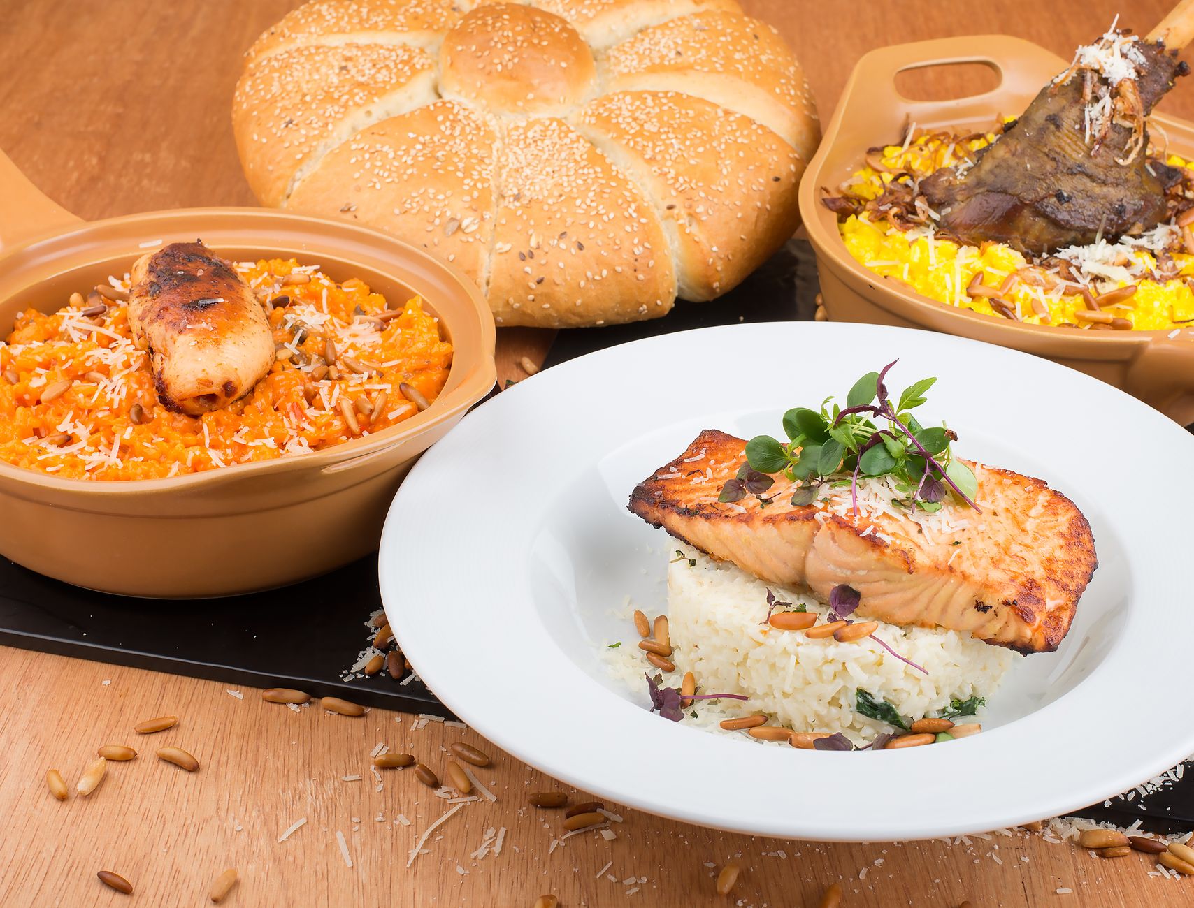 A delicious gourmet meal featuring grilled salmon, rice, and a variety of sides with freshly baked bread.