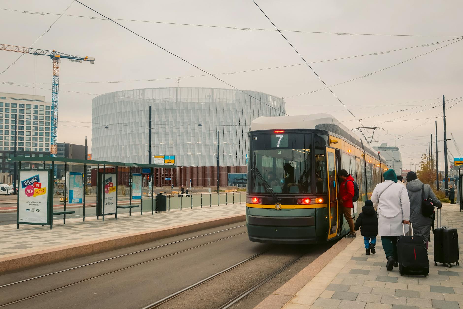 Passengers board a modern tram at Helsinki&rsquo;s winter station, a glimpse of urban life.
