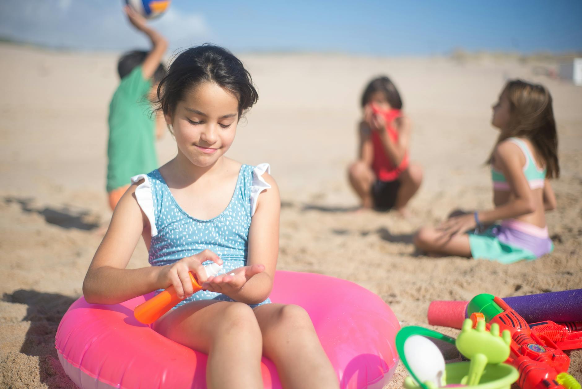 Children playing on a sunny beach, applying sunscreen, and enjoying summer activities.