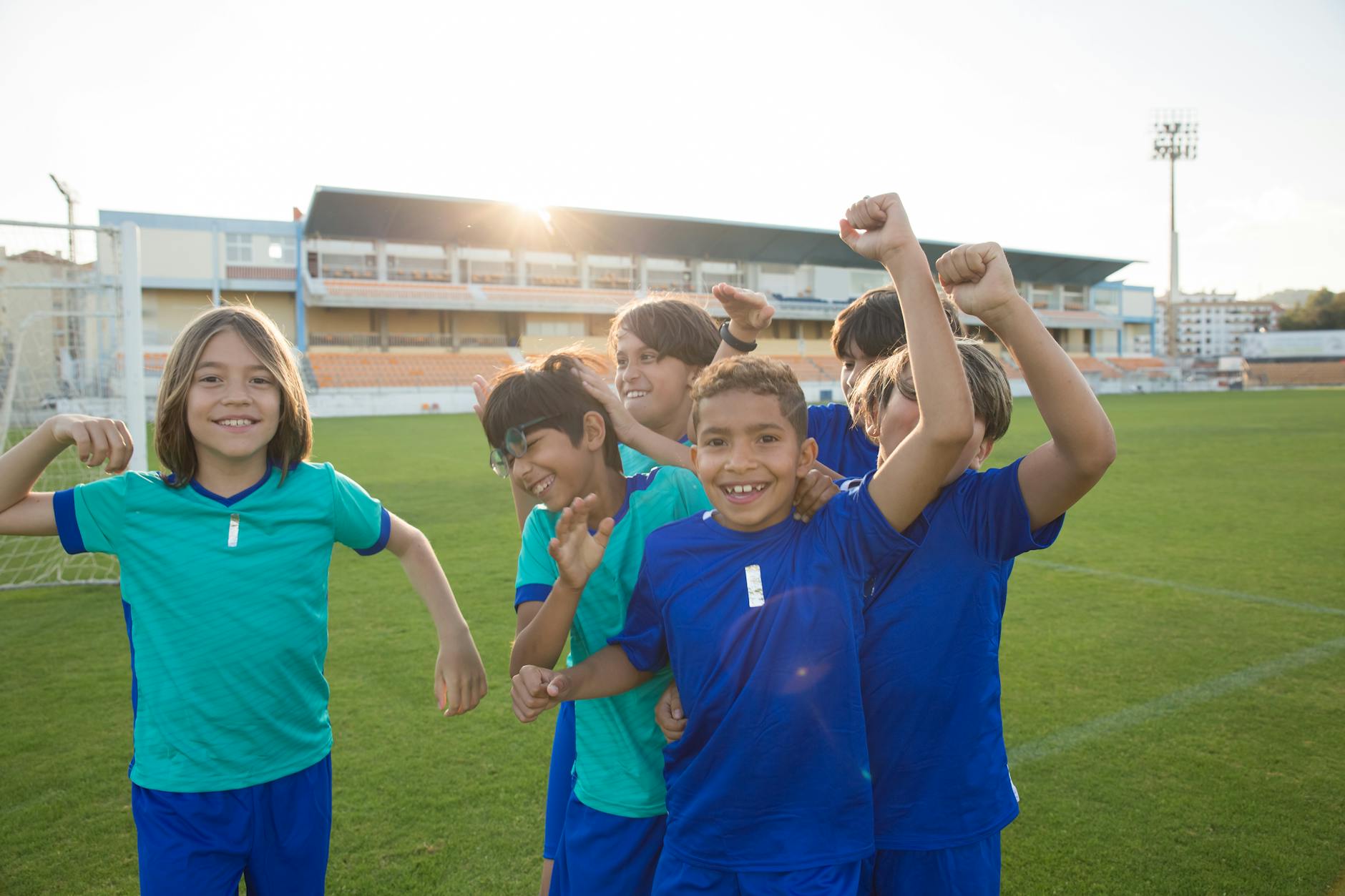 Happy group of children celebrating victory on a soccer field in Portugal.