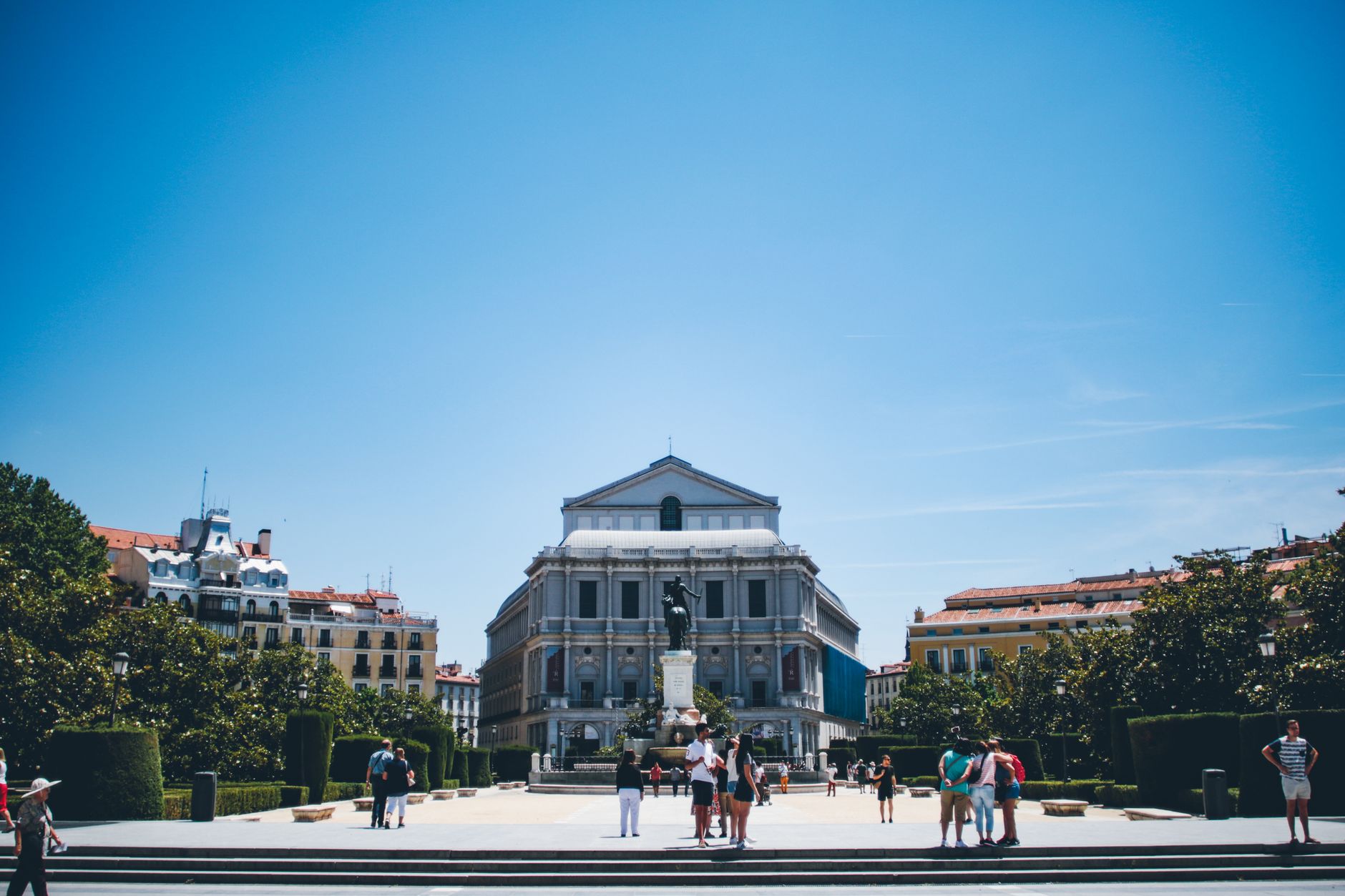 A vibrant daytime view of the Teatro Real and surrounding cityscape in Madrid, Spain.