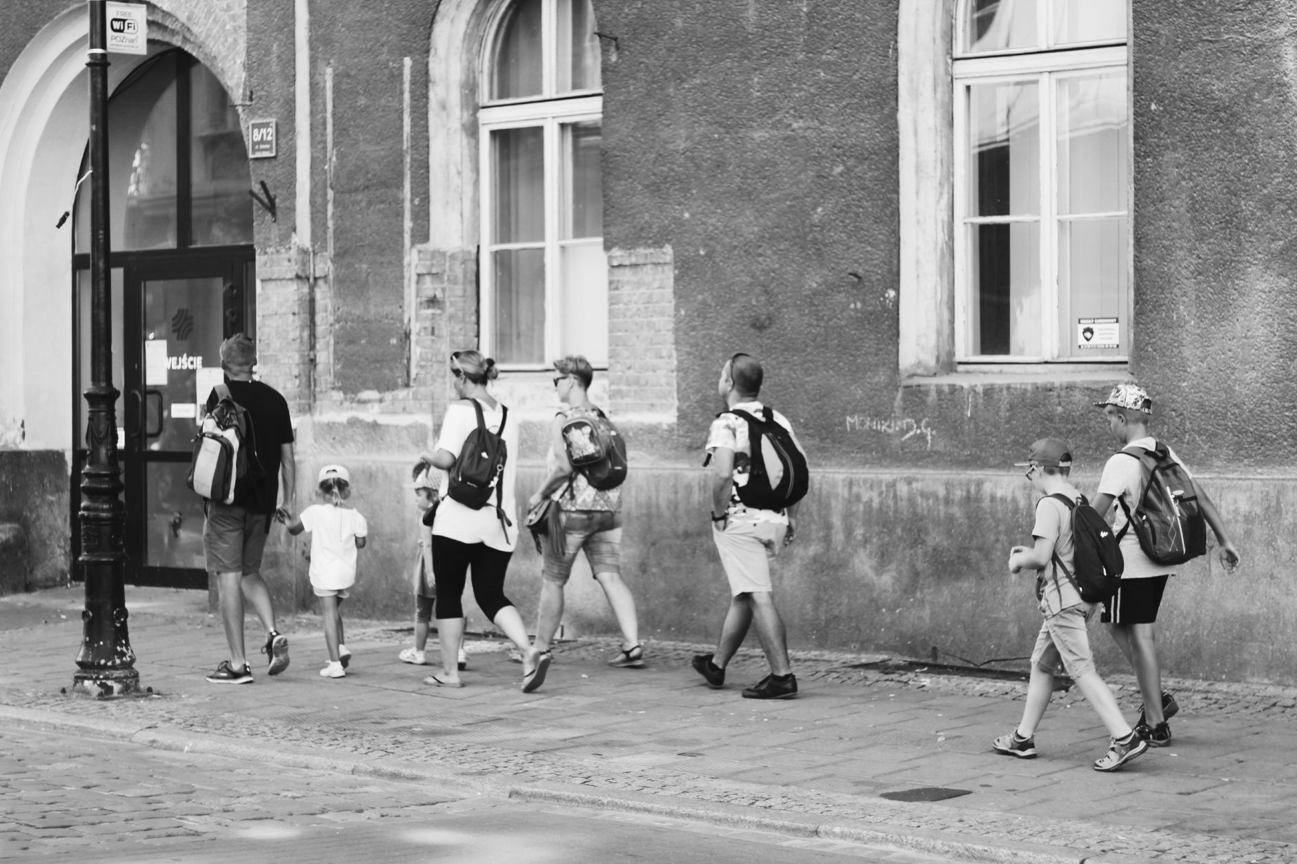 A group of people stroll together along a city street, exuding togetherness and exploration.
