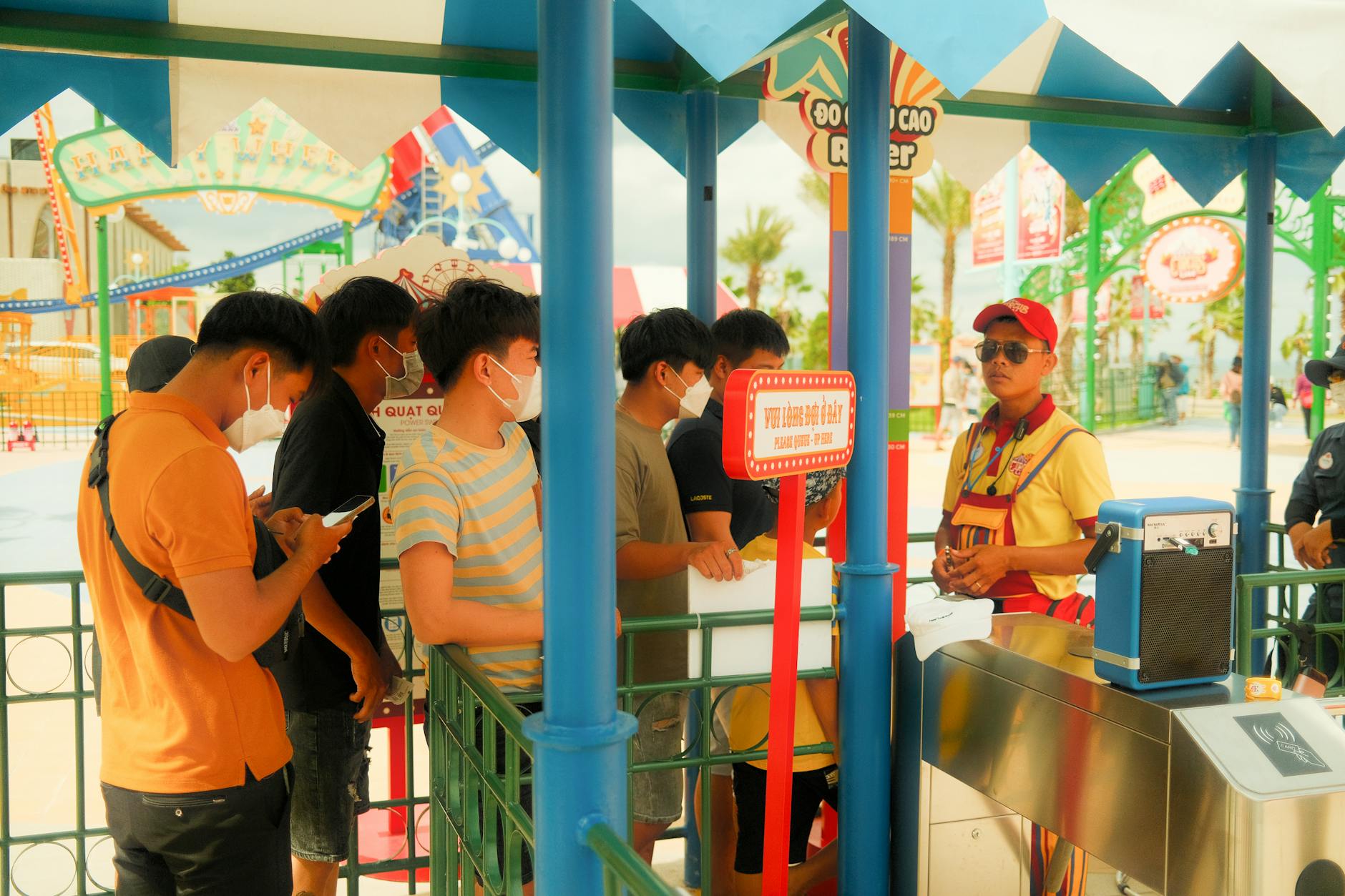People in masks queue at an amusement park, reflecting new COVID-19 health protocols.