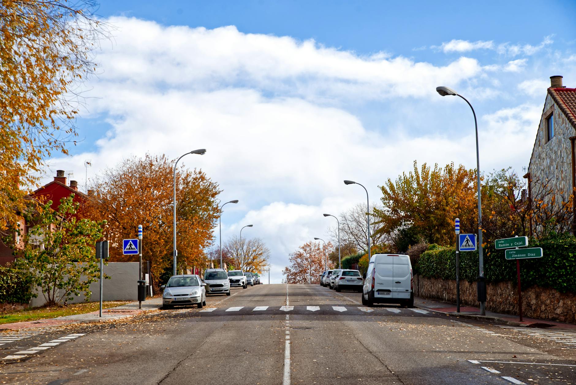 A serene street view in Pozuelo de Alarcón during autumn, capturing vibrant foliage and clear skies.