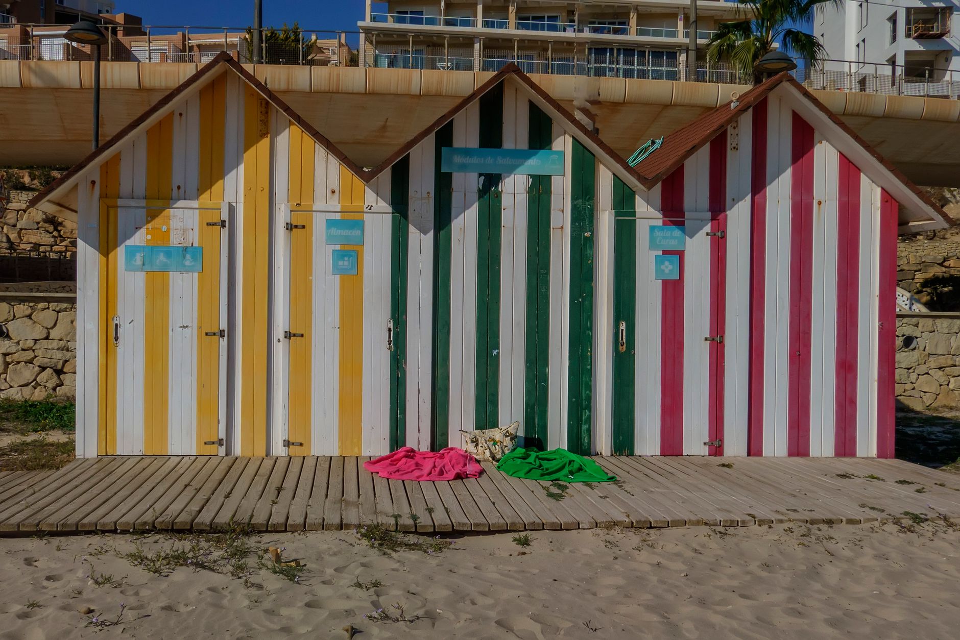 Vibrant striped beach huts on the sandy shores of Alicante, Spain.