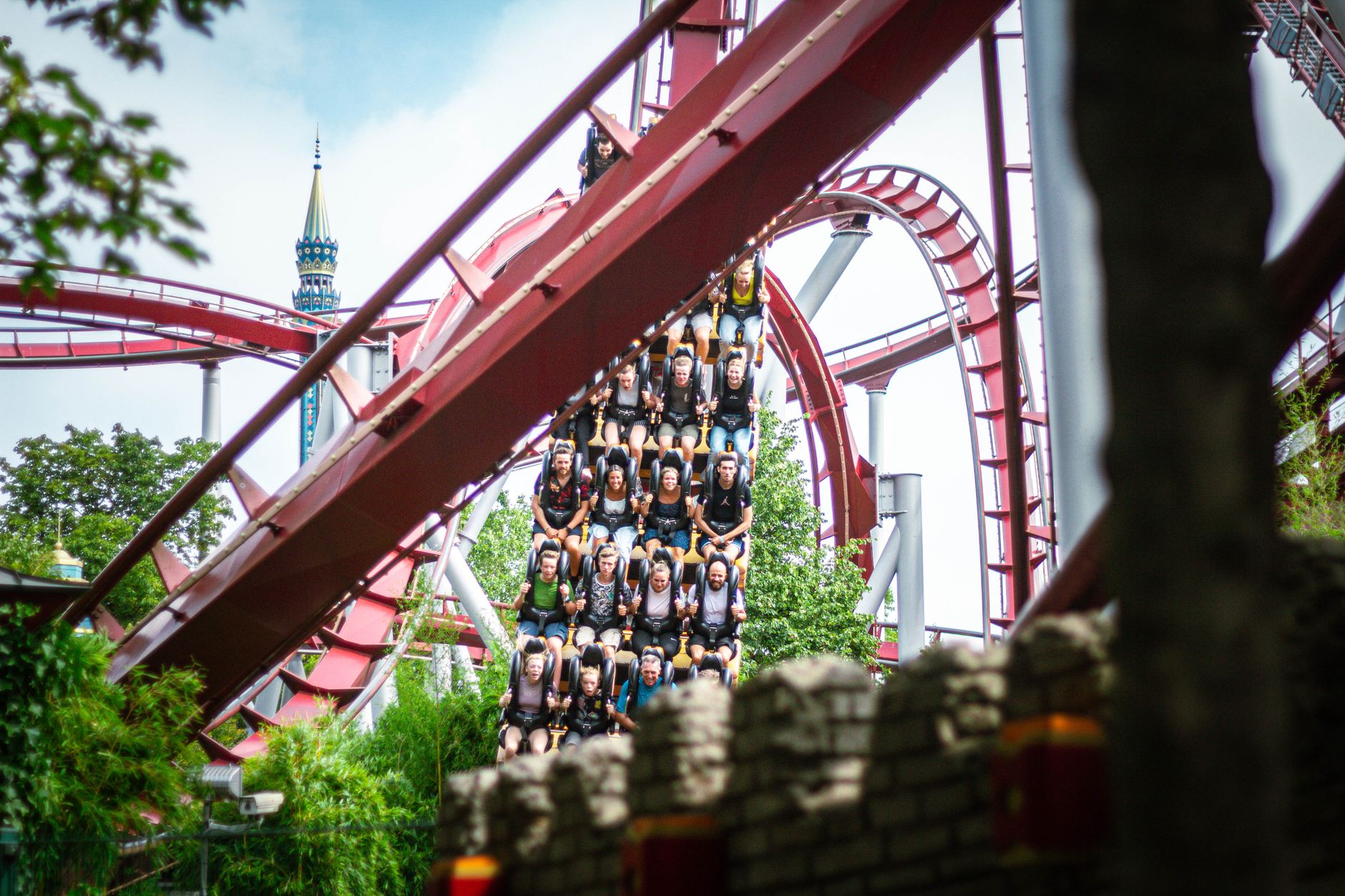 Experience the thrill of a roller coaster ride at a bustling amusement park during daytime.
