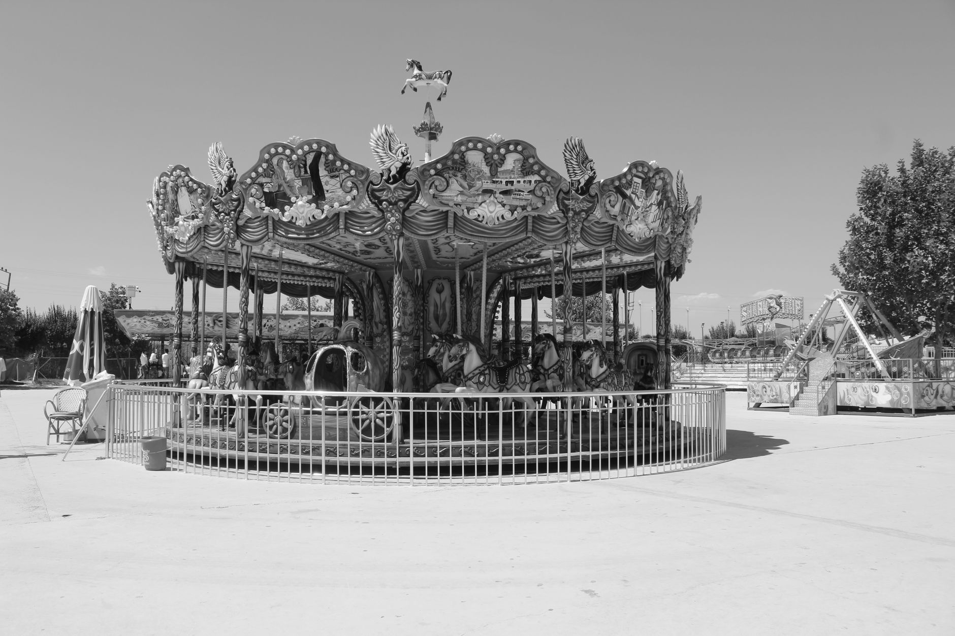 Vintage black and white carousel in an empty amusement park during summer day.