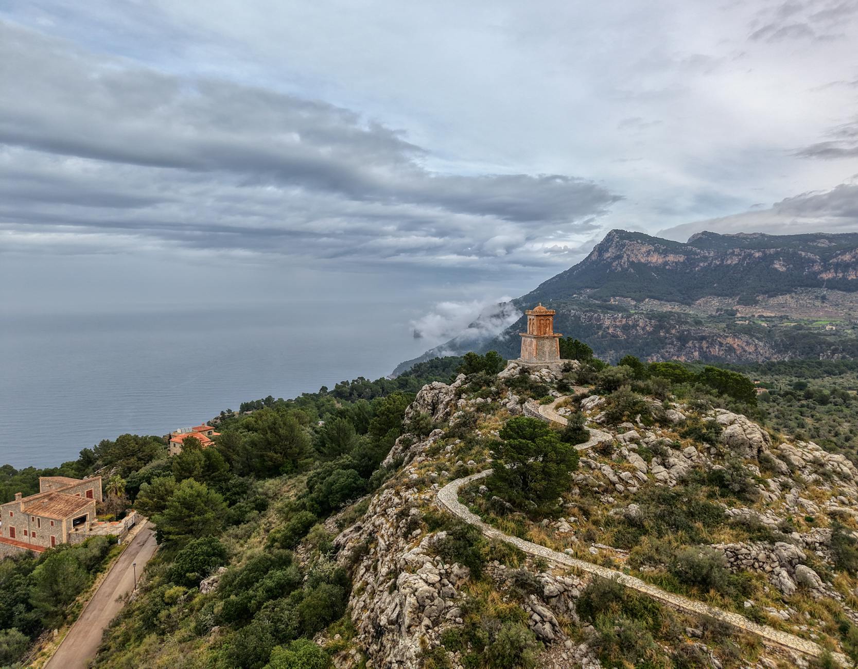 Stunning view of the rocky coastline and lush greenery of Mallorca, Spain, under a cloudy sky.