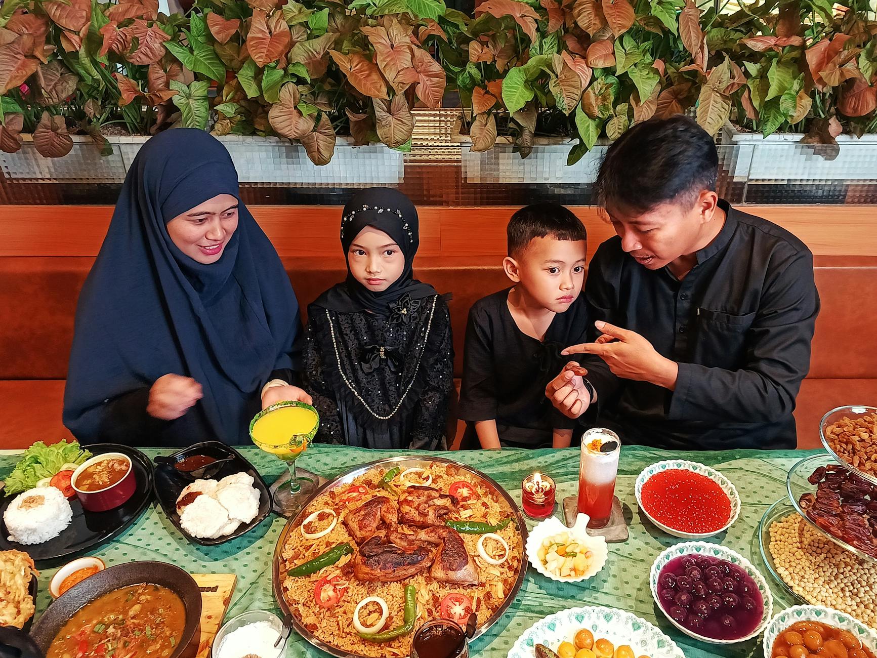A joyful Indonesian family gathers around a festive meal, showcasing traditional dishes in a warm setting.