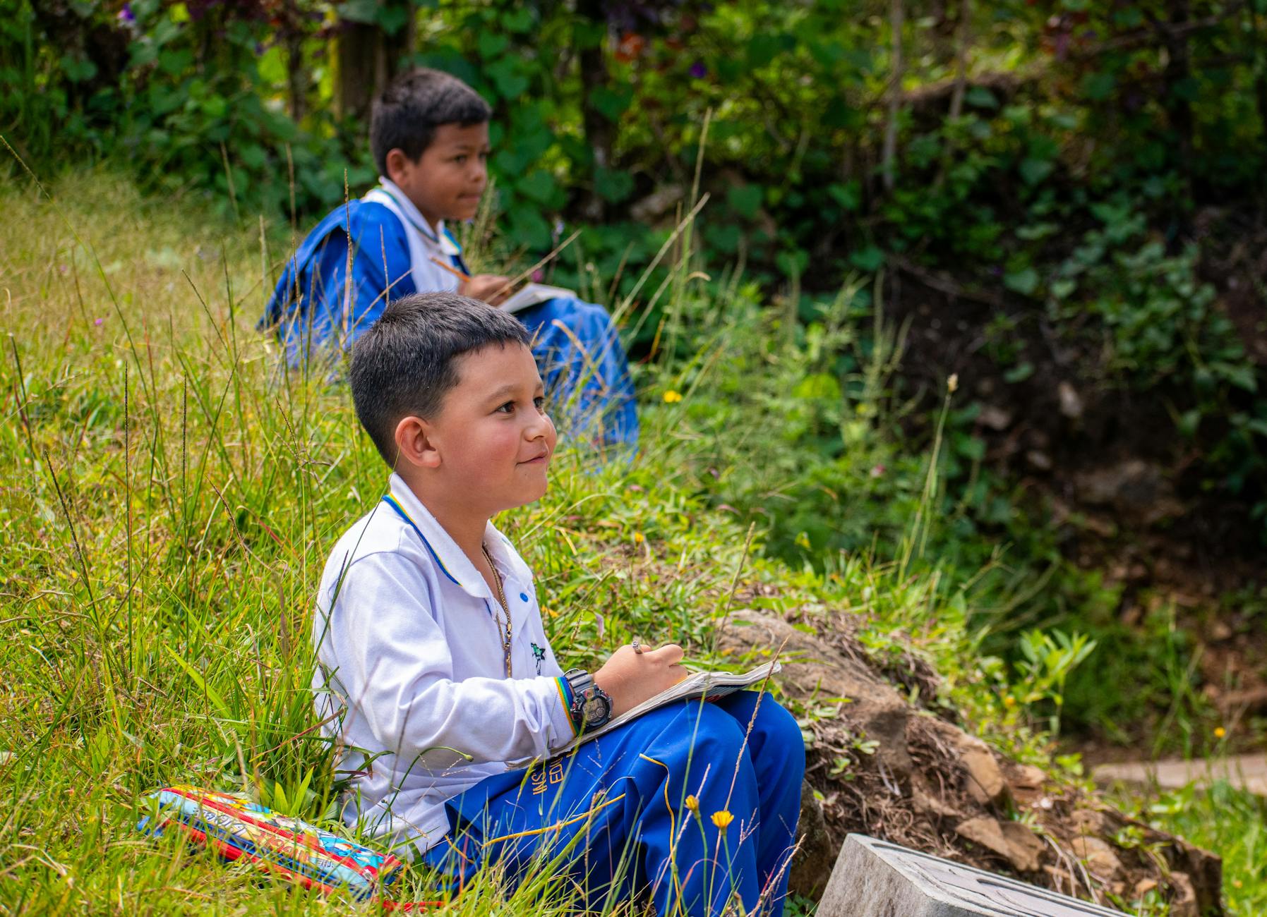 Two children studying outside amidst nature in Caicedo, Antioquia, Colombia.