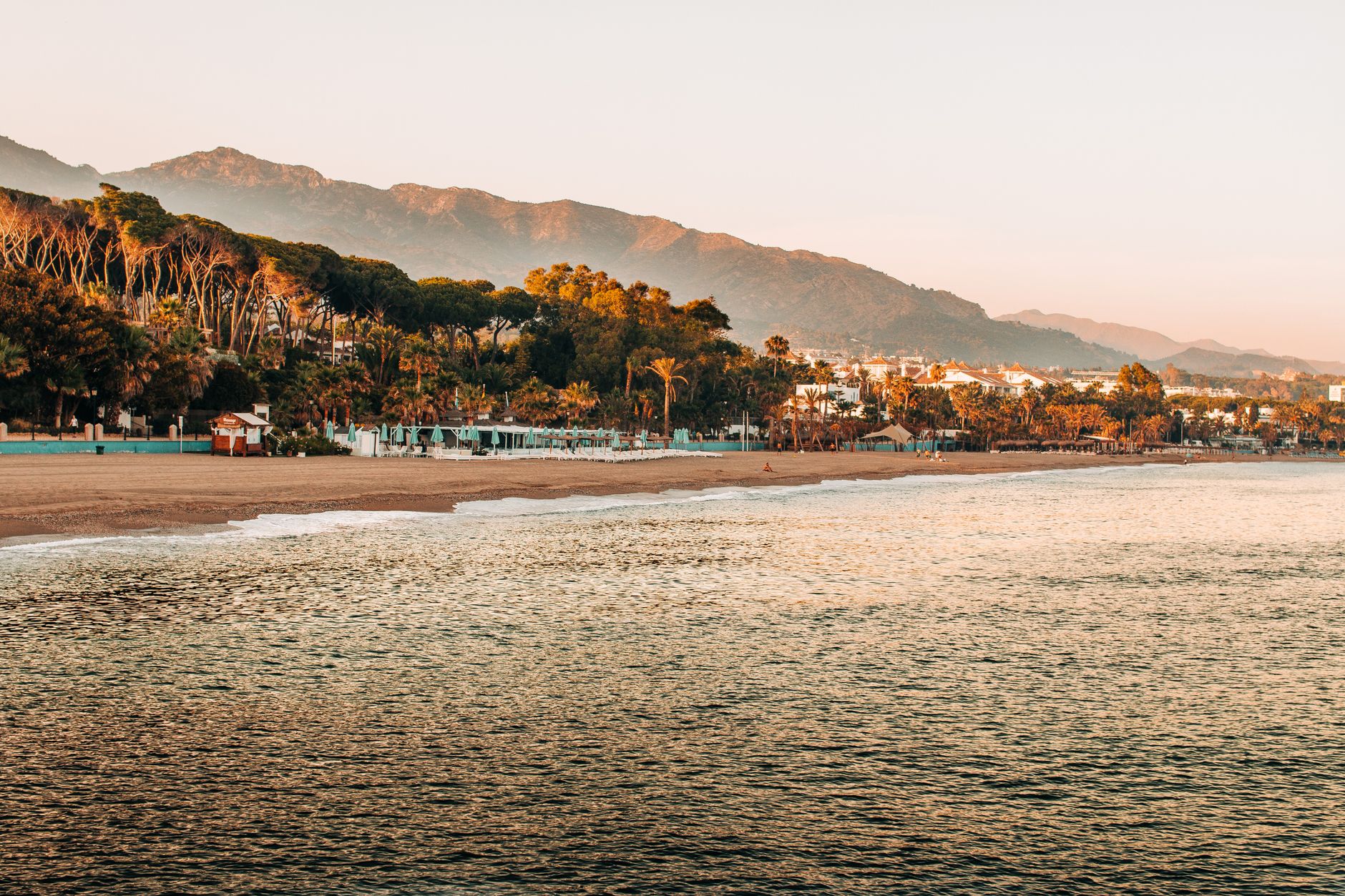 Peaceful sunrise view of Marbella’s beach with mountains and lush greenery in Spain.