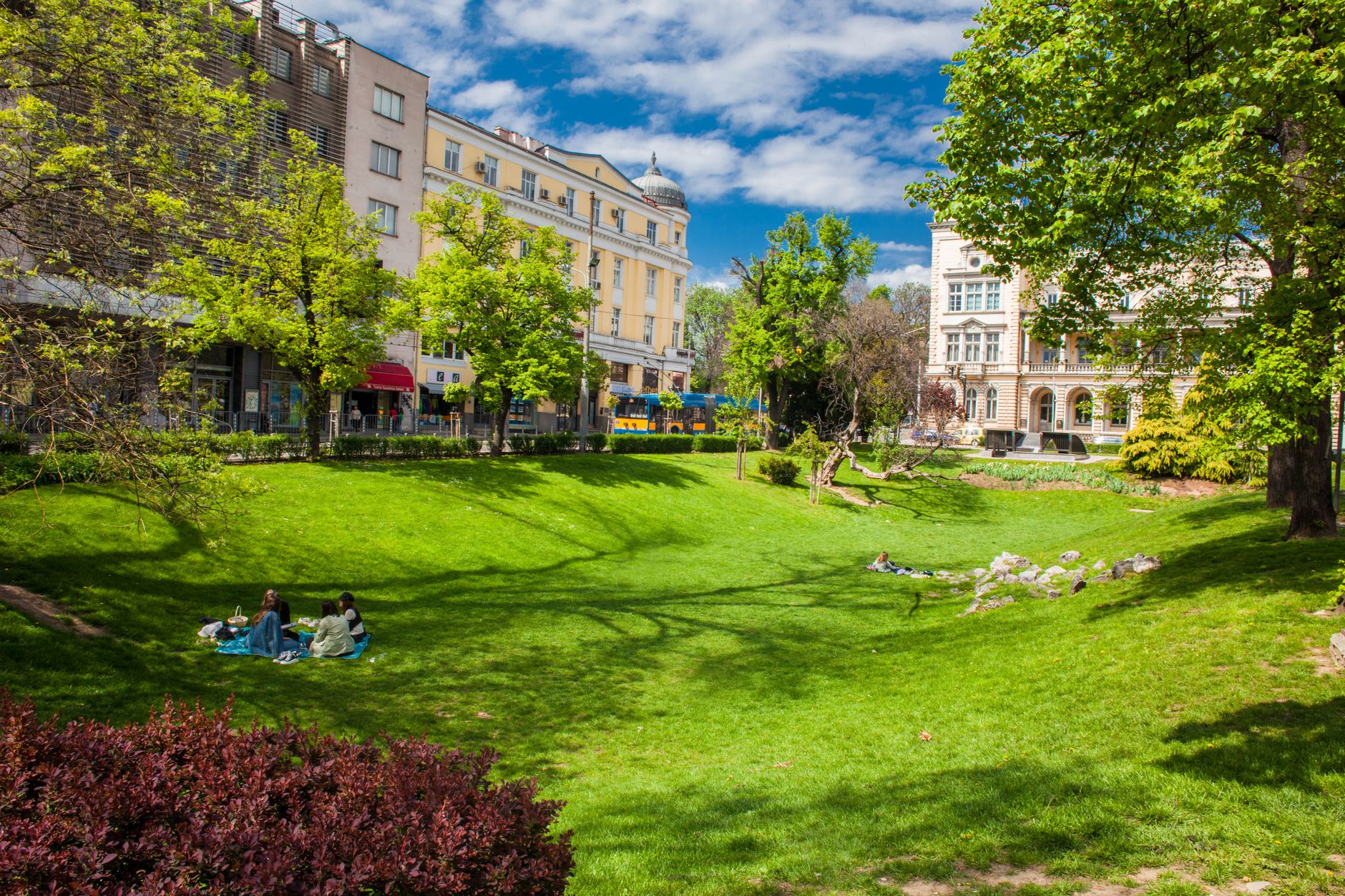 People enjoying a relaxing picnic in a lush green park surrounded by beautiful architecture.