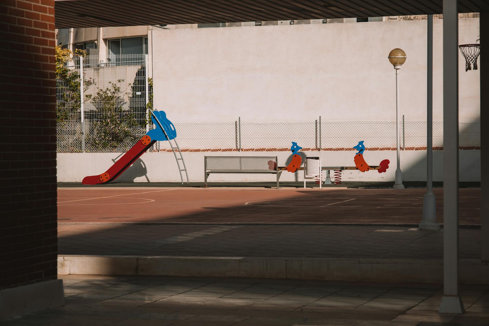 A deserted playground with a colorful slide and urban surroundings in Valencia, Spain.