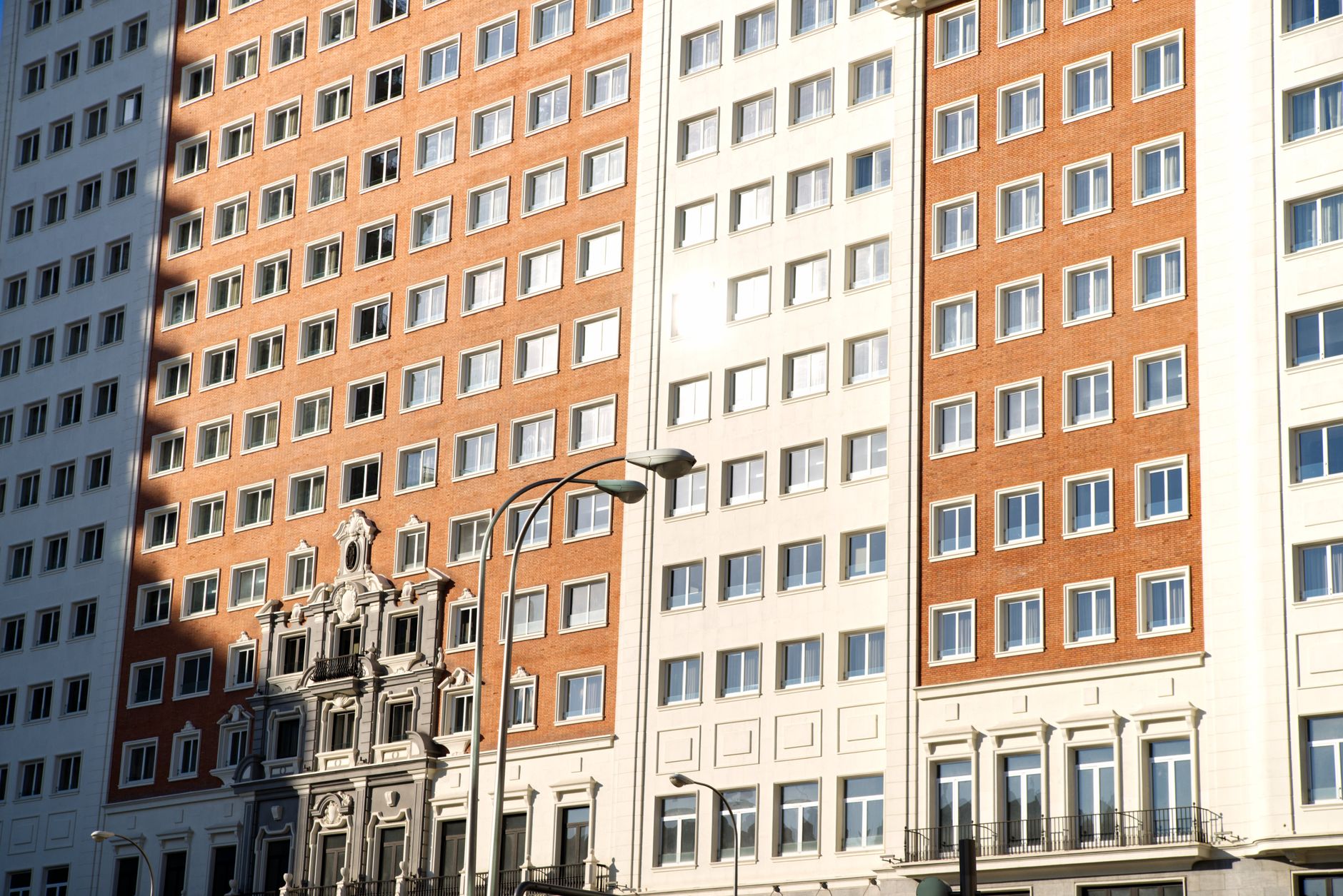 Sunlit facade of a classic residential building with windows in Madrid, Spain.