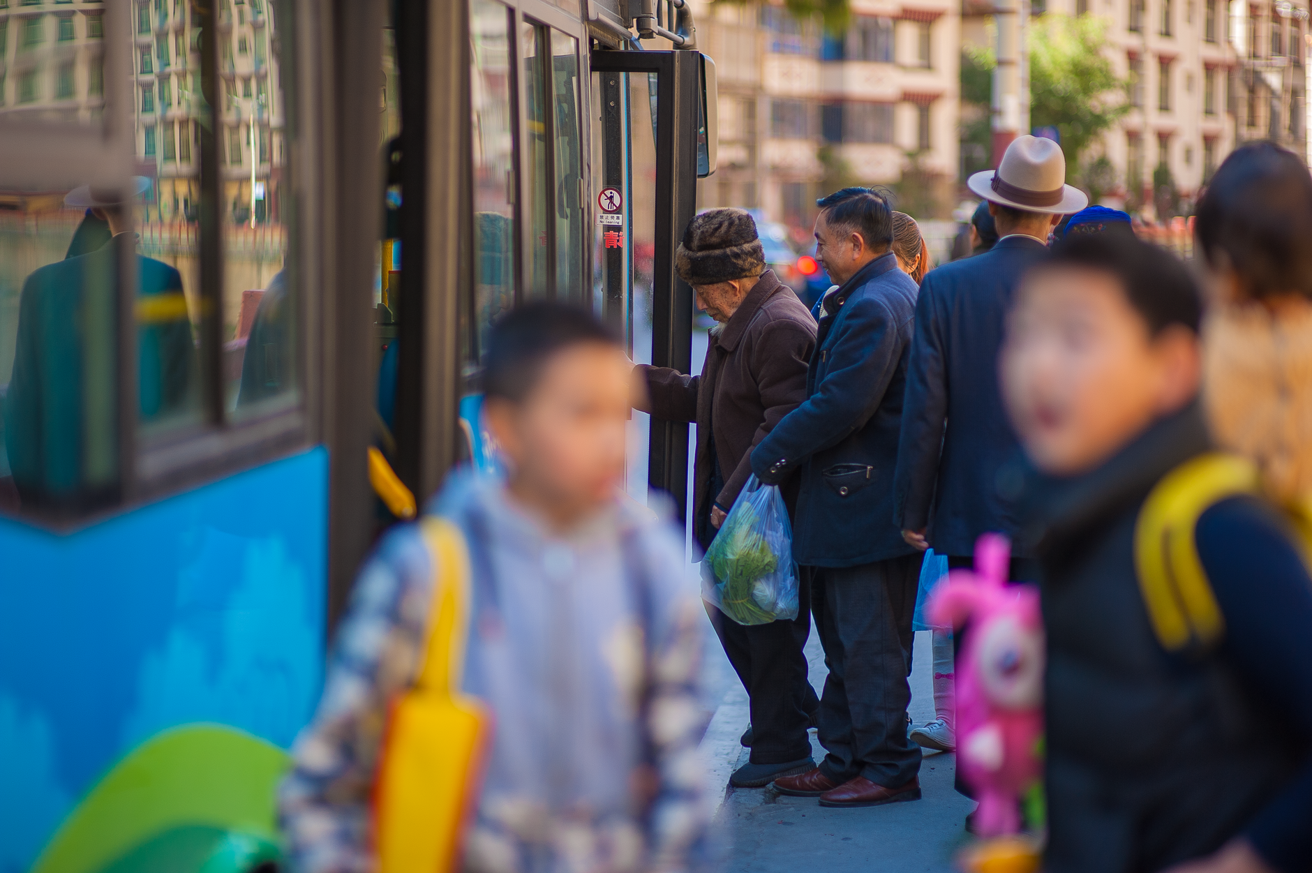 A group of people, including children and adults, boarding a city bus on a bustling urban street.