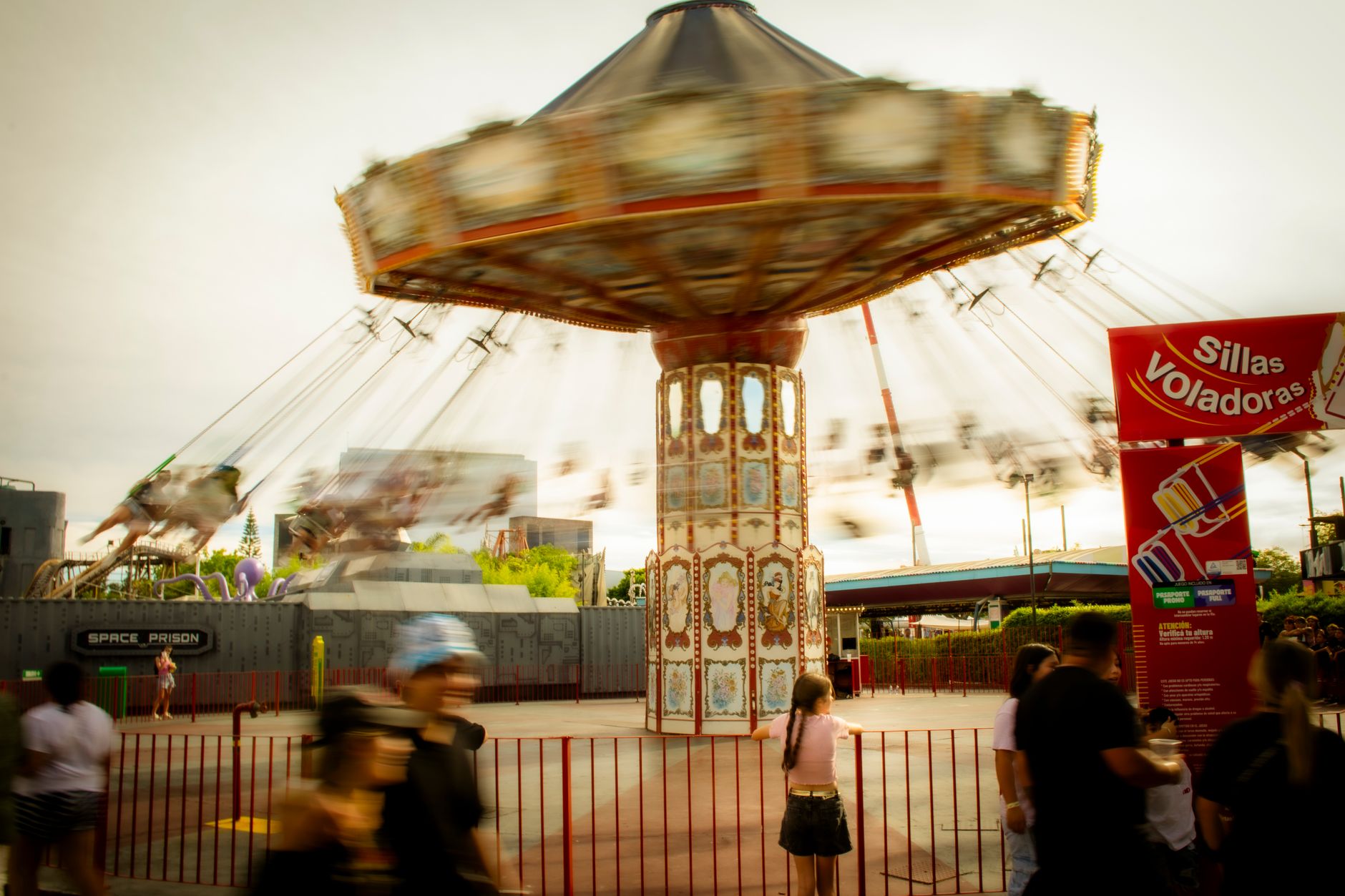 Blurred motion of a swing ride in an amusement park with people watching.