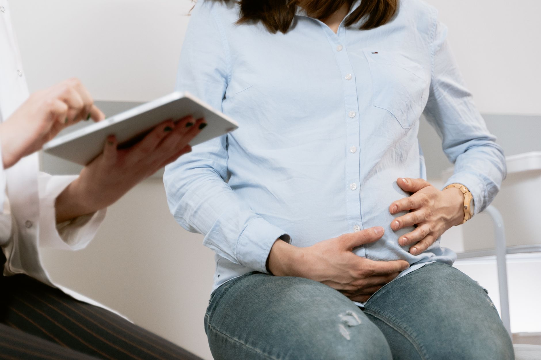 Pregnant woman attending a healthcare consultation, showcasing doctor-patient interaction.