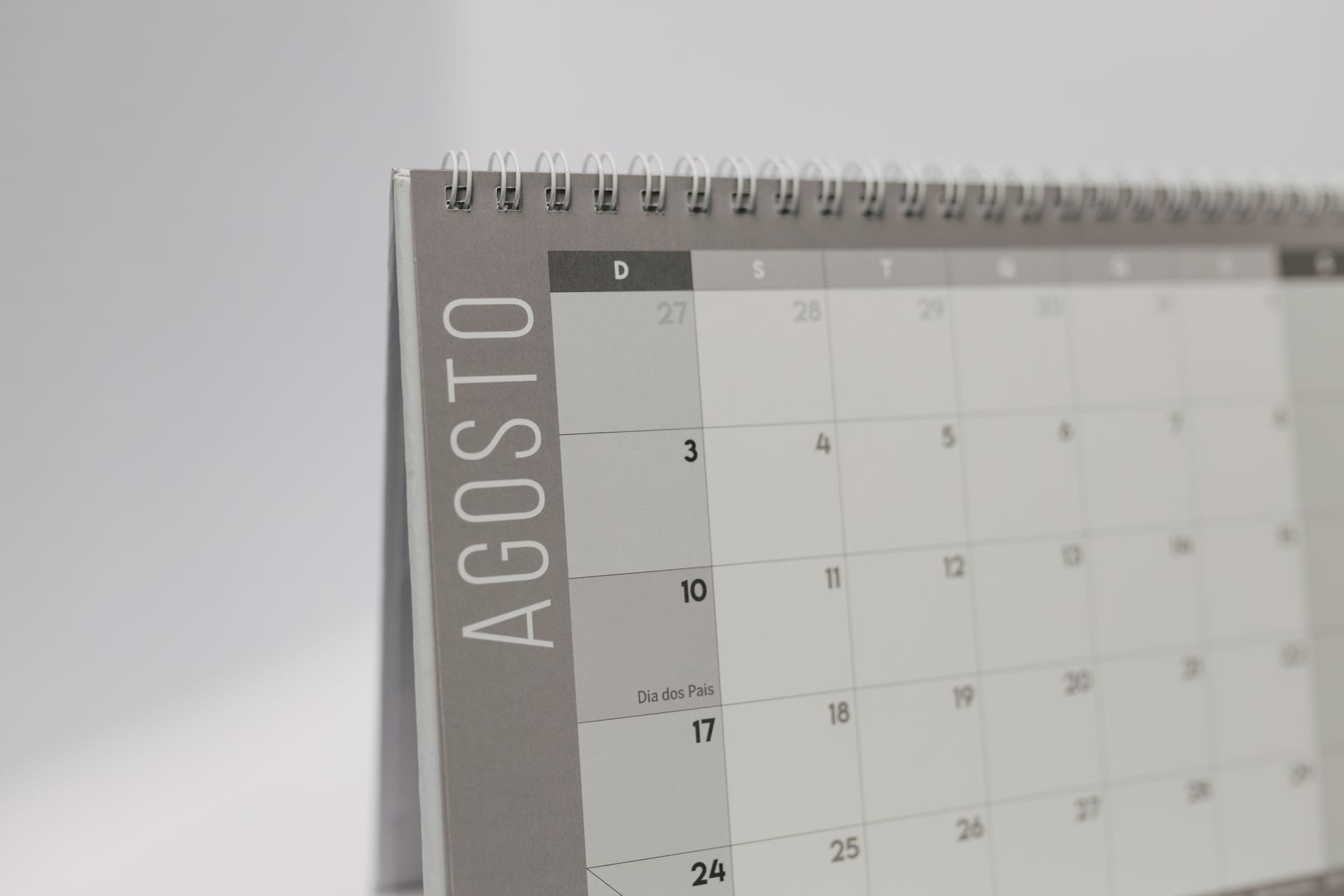 Close-up of a desk calendar showing August in Portuguese with a minimalist layout.