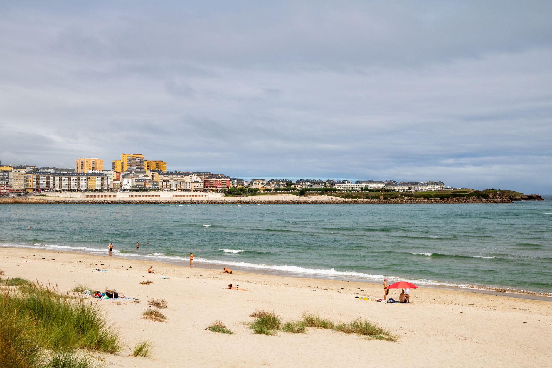 Relaxing summer day at the beach in Foz, Galicia, Spain, with ocean waves and coastal town.