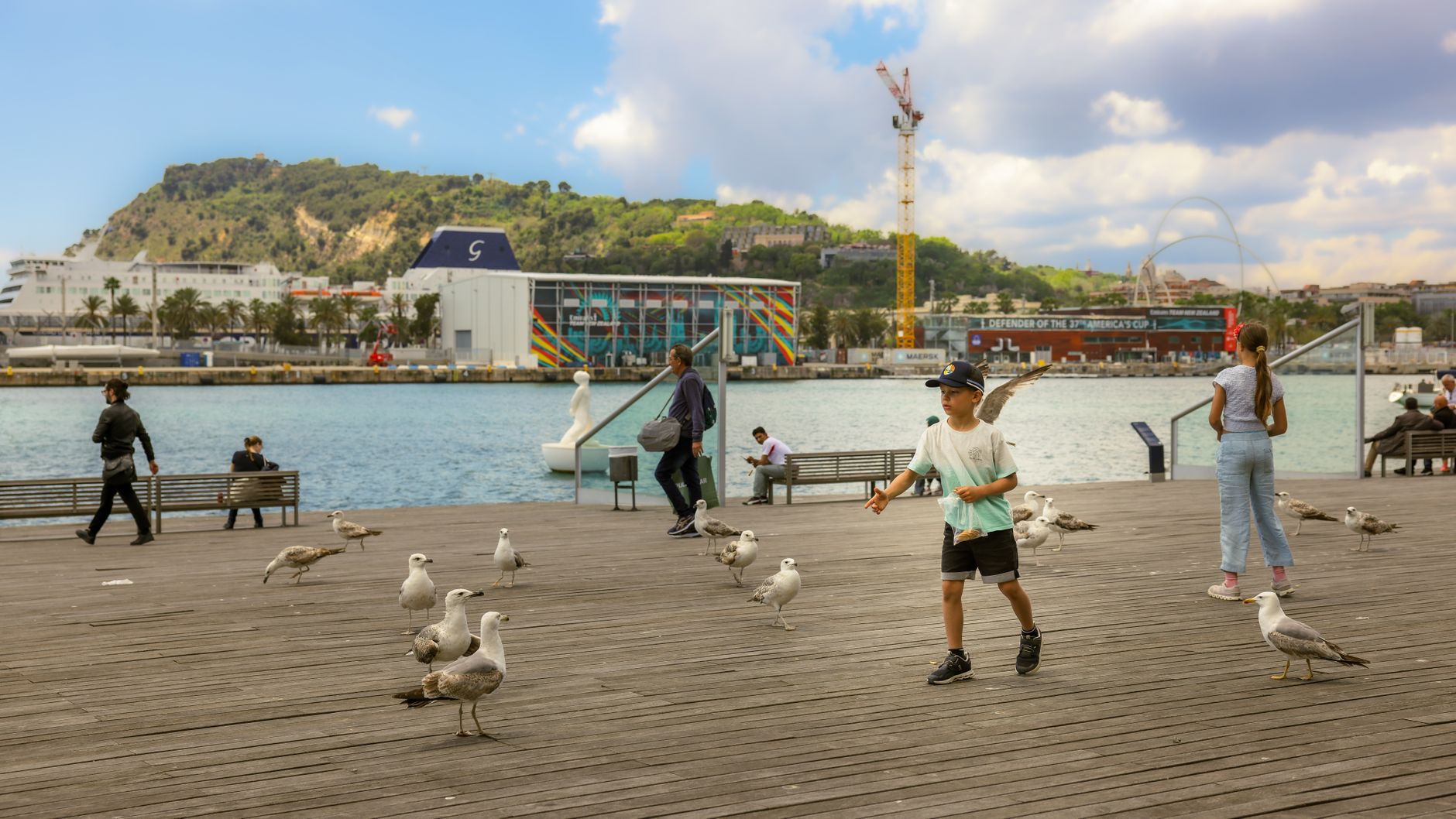 People enjoying a seaside walk with seagulls at Barcelona&rsquo;s waterfront.