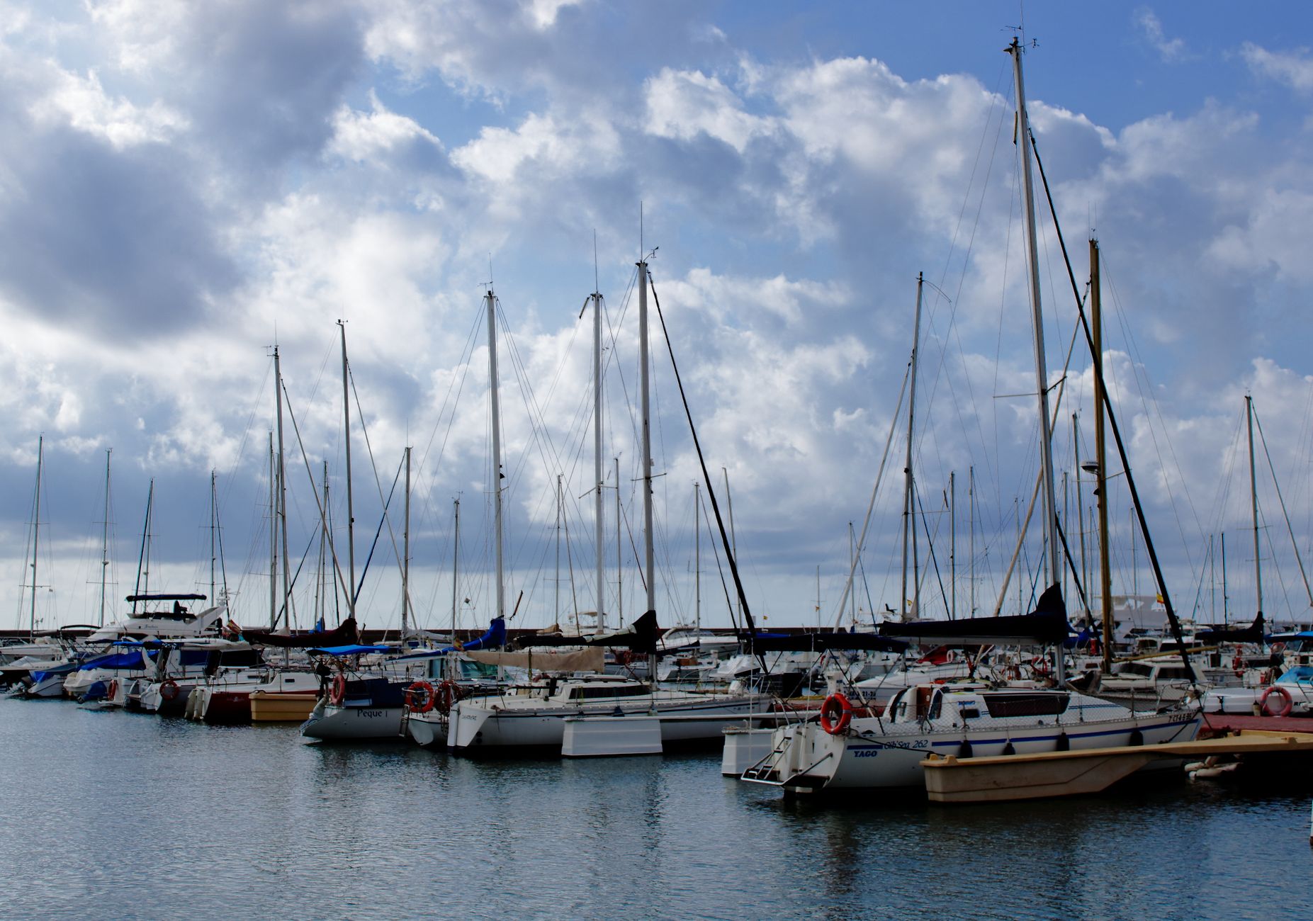 Scenic view of sailboats at a marina in Valencia, Spain under a cloudy sky.