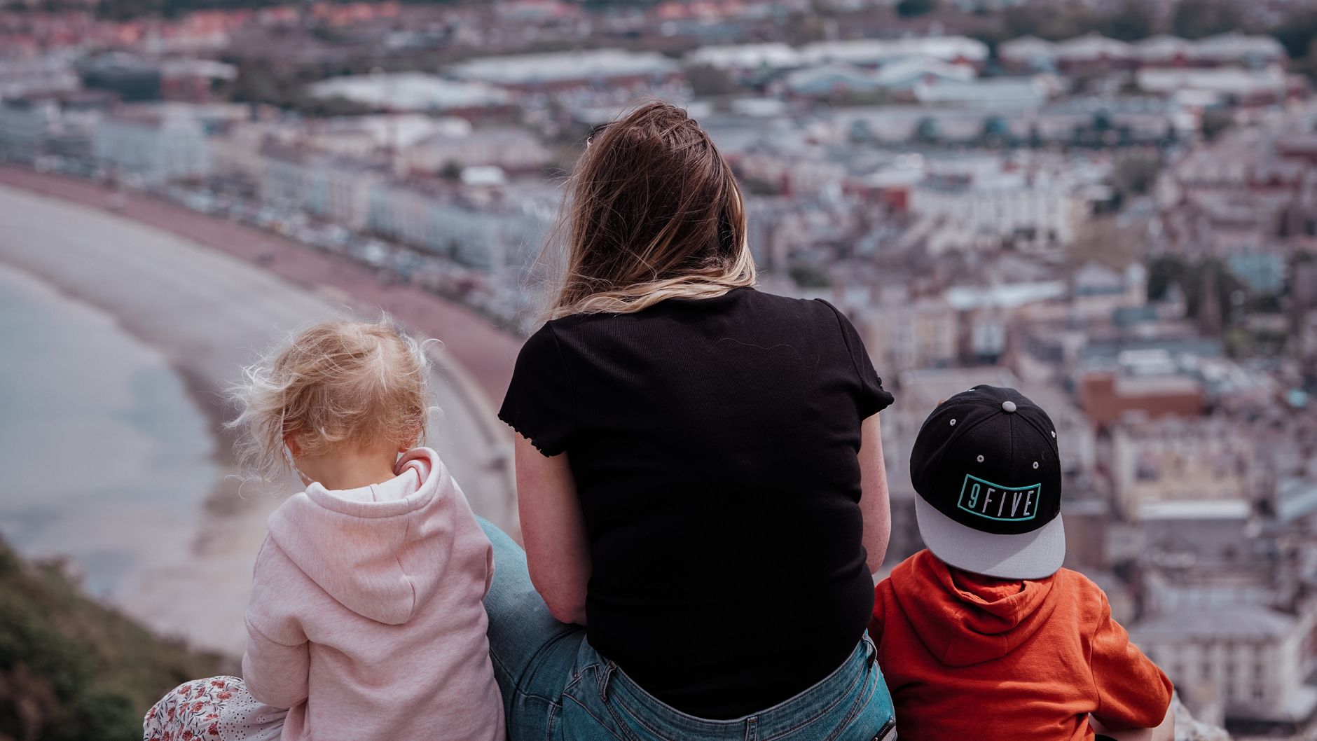 A mother and two children enjoy the scenic view of Llandudno from a hilltop in Wales.