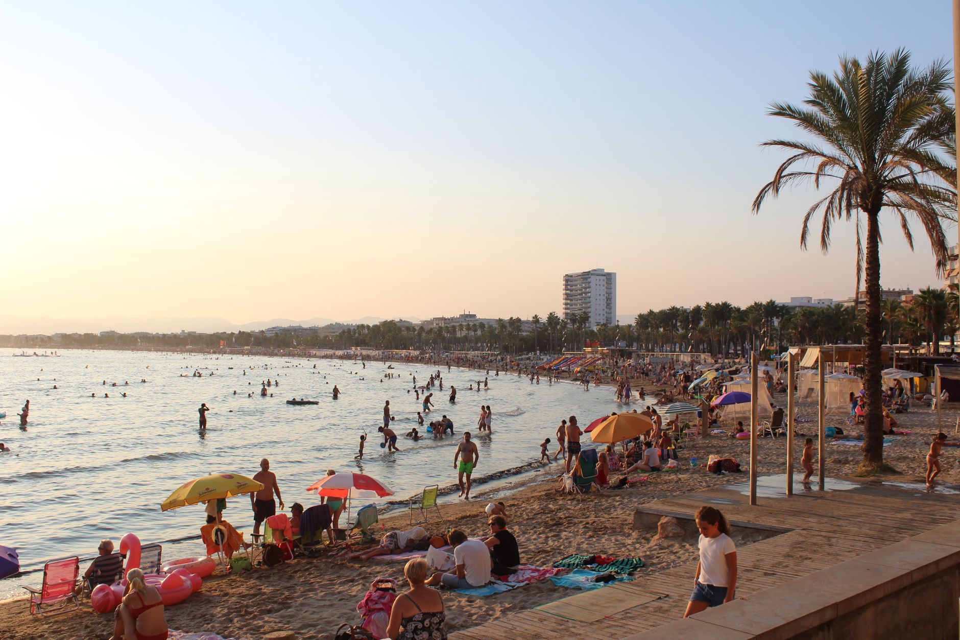 Crowded beach in Spain with people enjoying a sunny day at the shore.