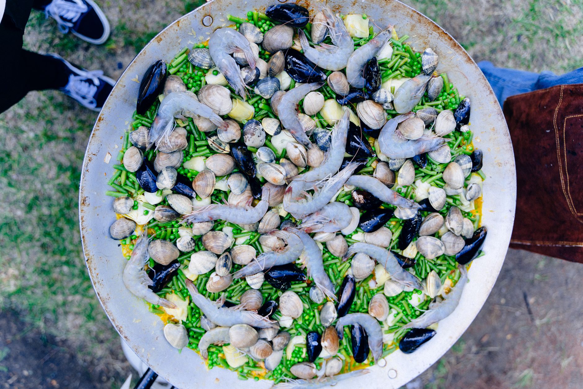 Close-up of uncooked seafood paella with clams, mussels, and shrimps in a large pan outdoors. Perfect for culinary travel.