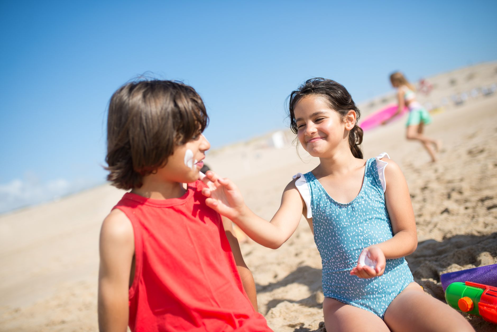 Children playing and applying sunscreen on a sunny beach in Portugal. Perfect summer vacation scene.