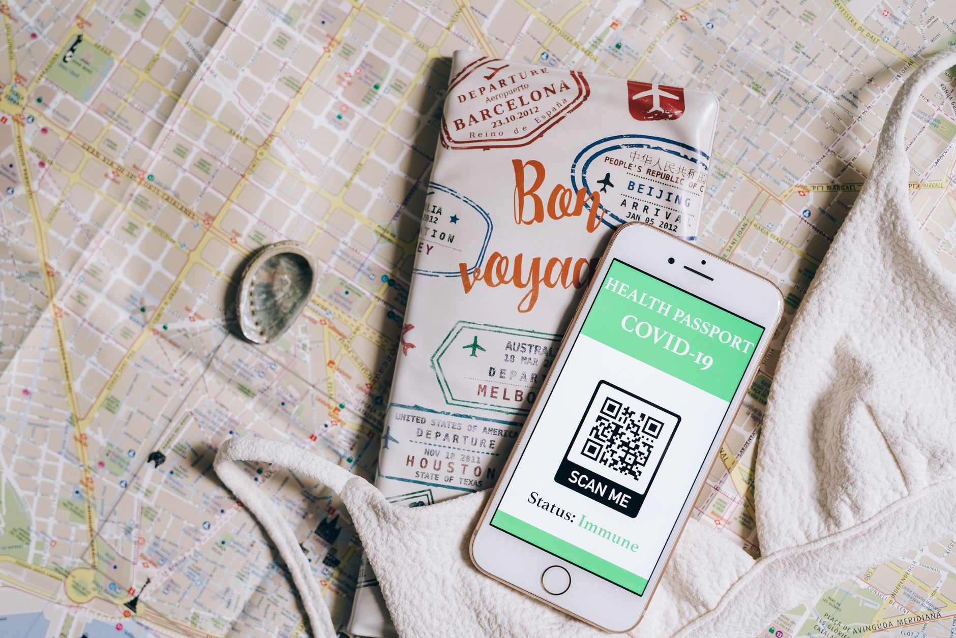 Smartphone displaying a health passport with QR code on a travel map and passport cover.