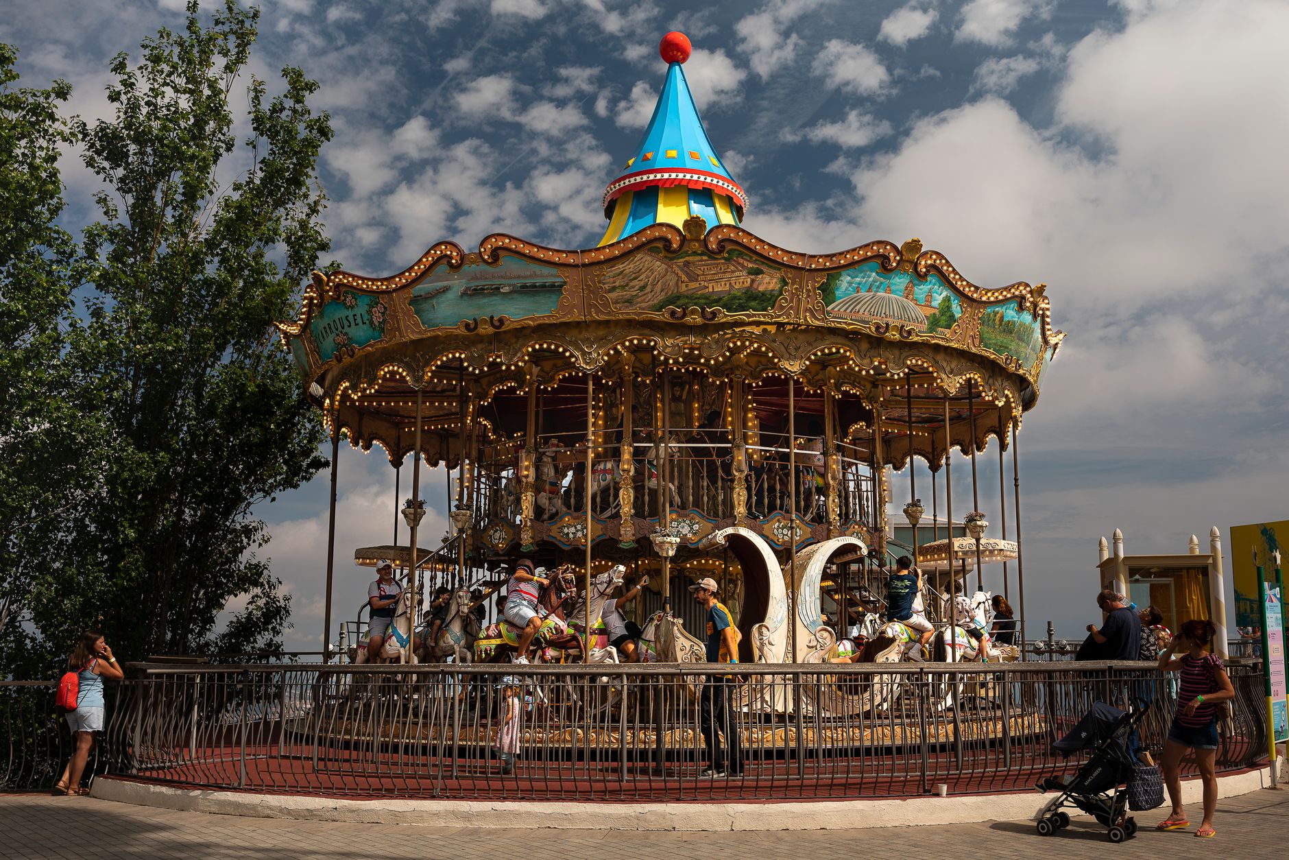 Vibrant carousel with people enjoying a sunny day at Tibidabo in Barcelona.