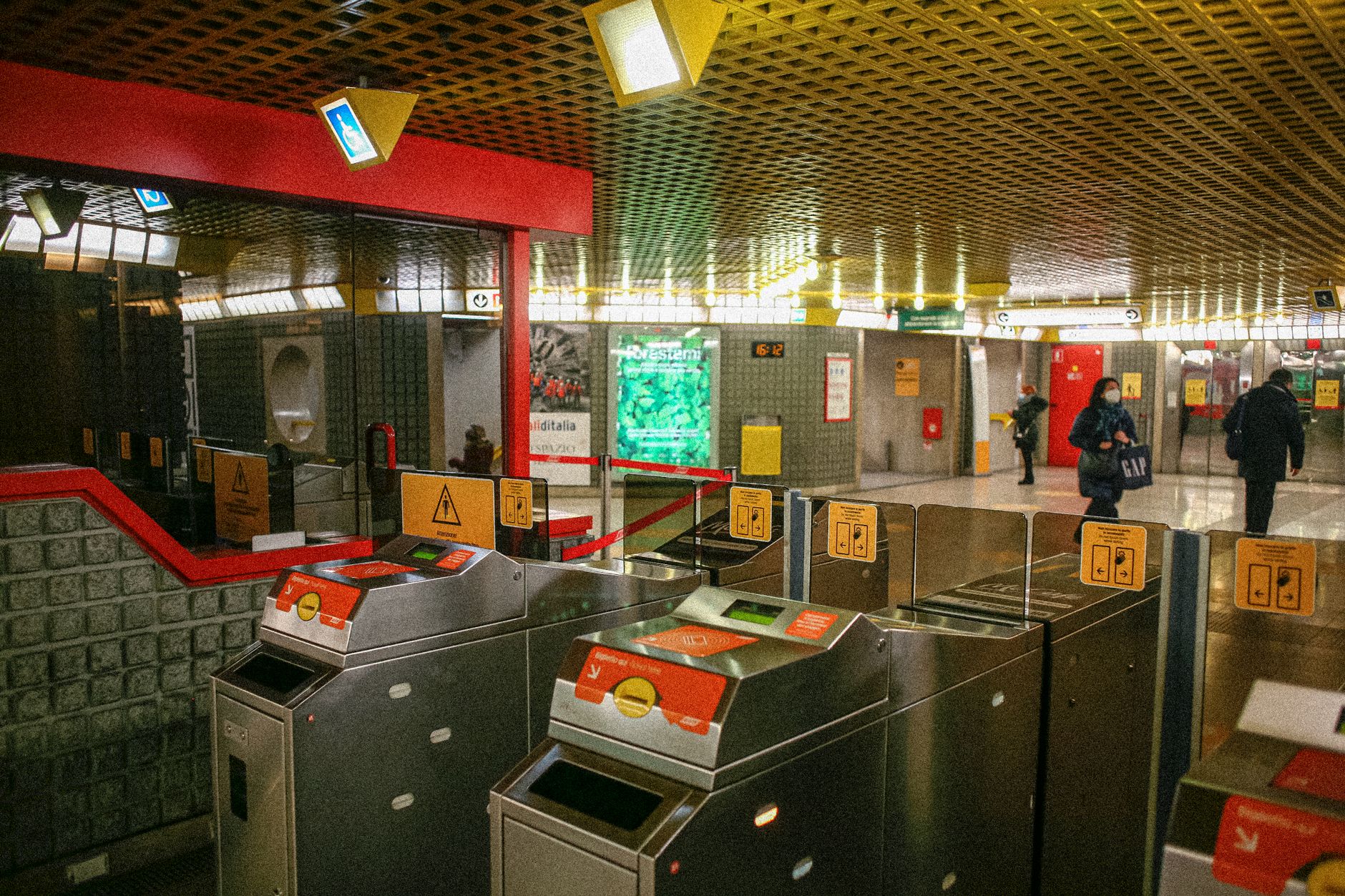 Ticket gates at a busy Milano metro station, showcasing public transit infrastructure.