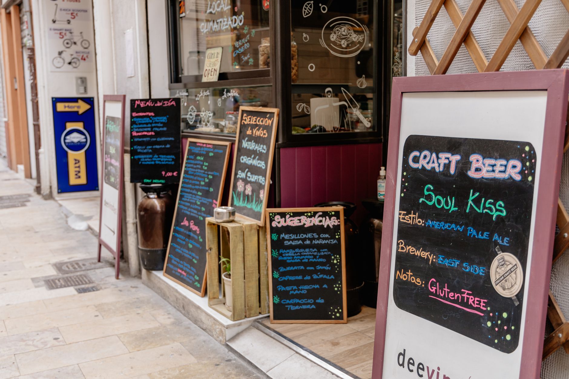 Outdoor view of a cafe in Valencia, Spain showcasing decorative chalkboard menus and vibrant signage.