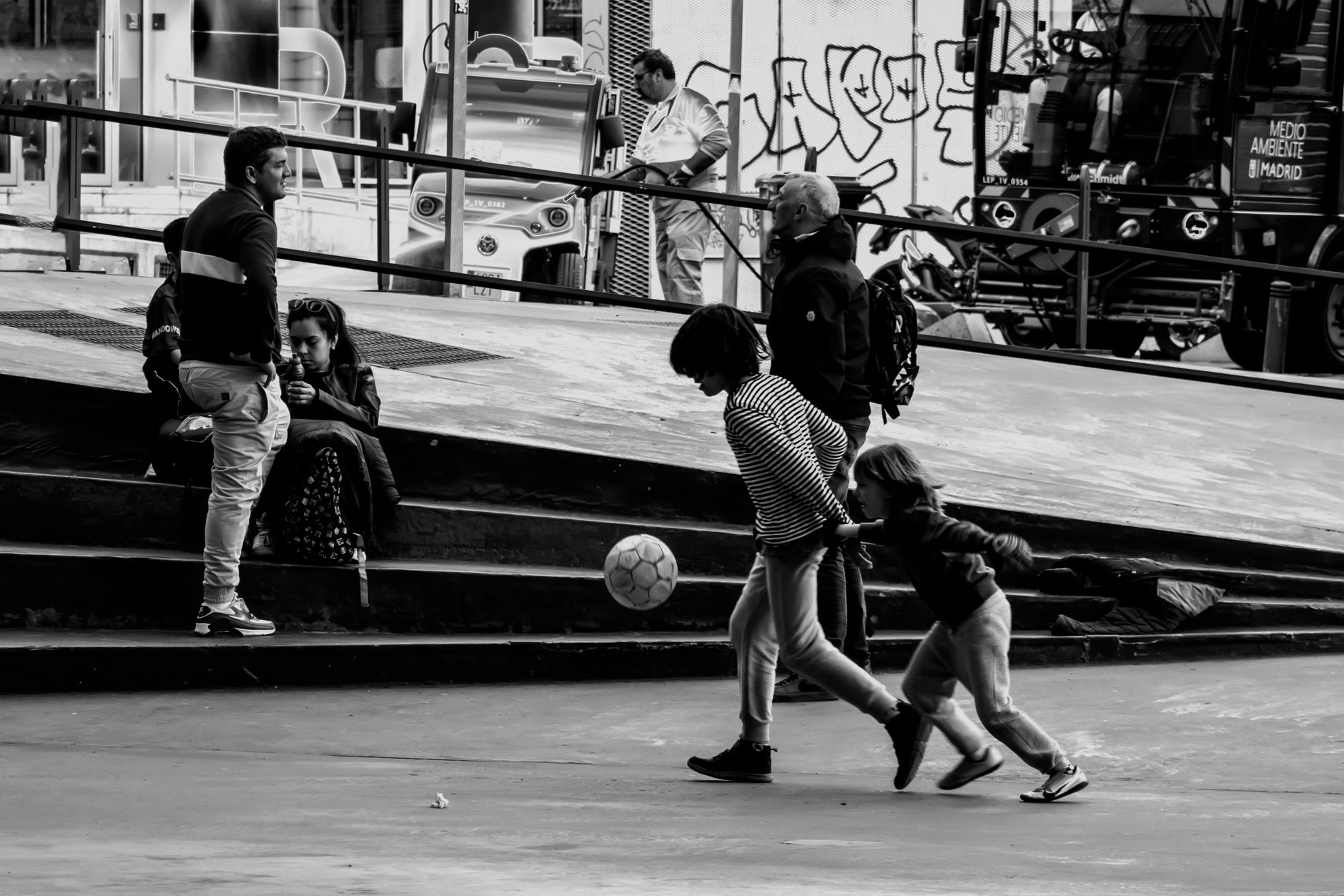 Children playing soccer in a Madrid skate park, capturing urban leisure and community spirit.