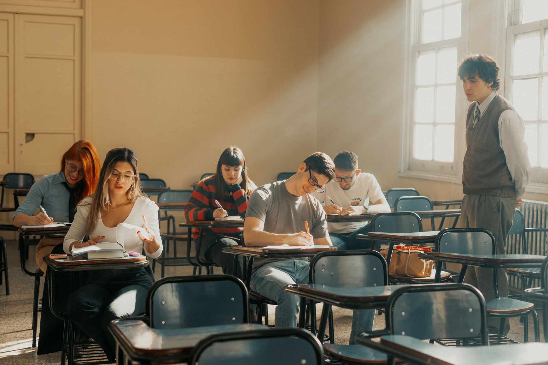 Students attending a lecture in a Buenos Aires university classroom, sunlight streaming in.
